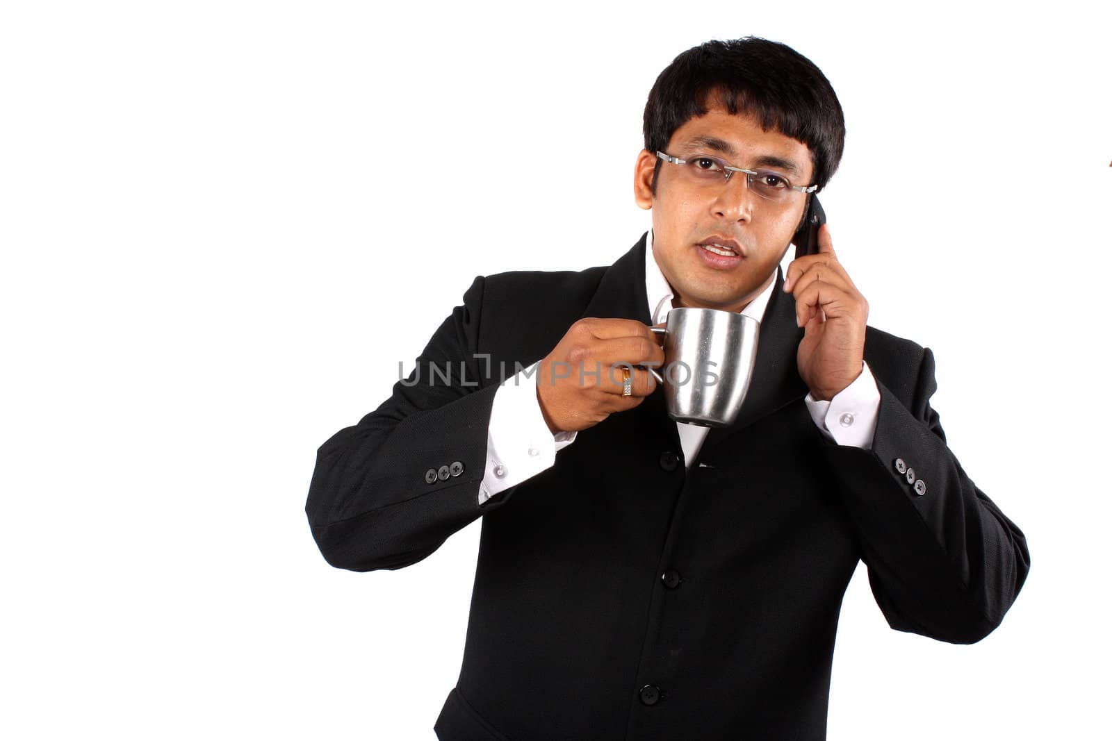An Indian businessman talking on the cellphone during the coffee break, on white studio background.