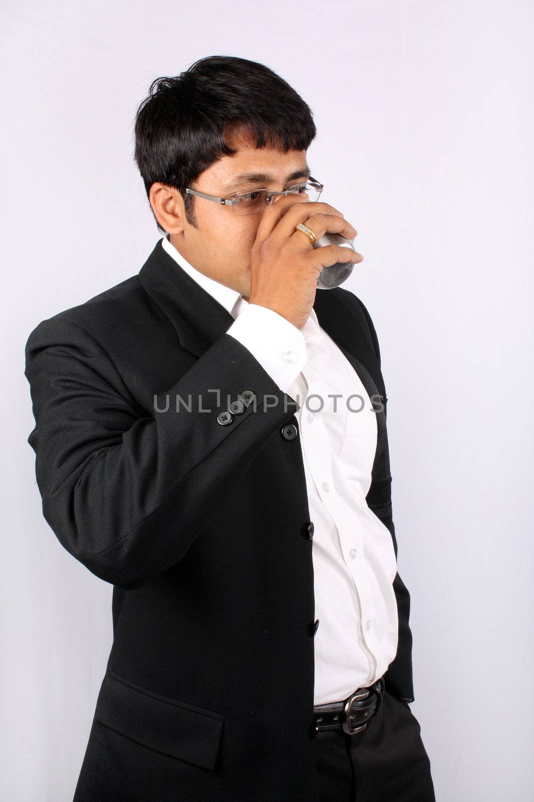 An Indian businessman drinking coffee during office break, on white studio background.
