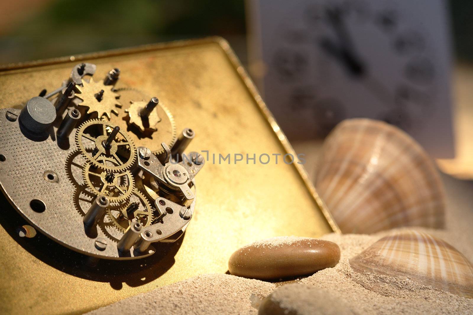 Abstract background with old clock mechanism standing on sand with stones and shells