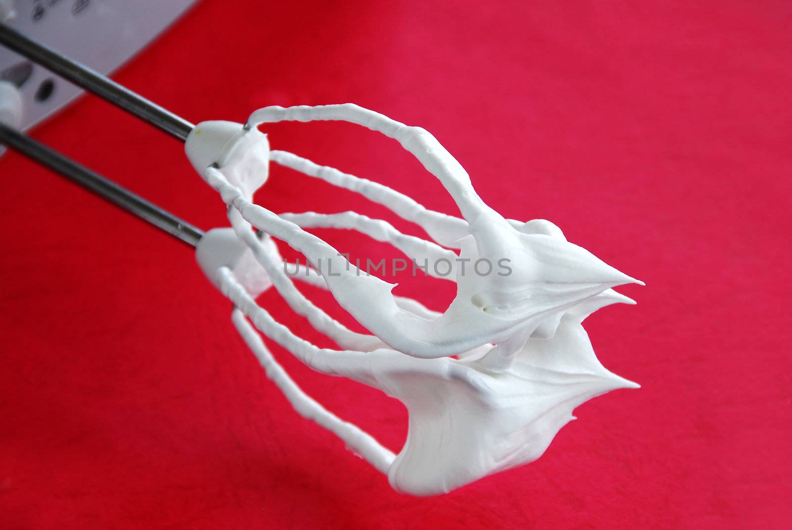 mixer whisks with white cream over red background