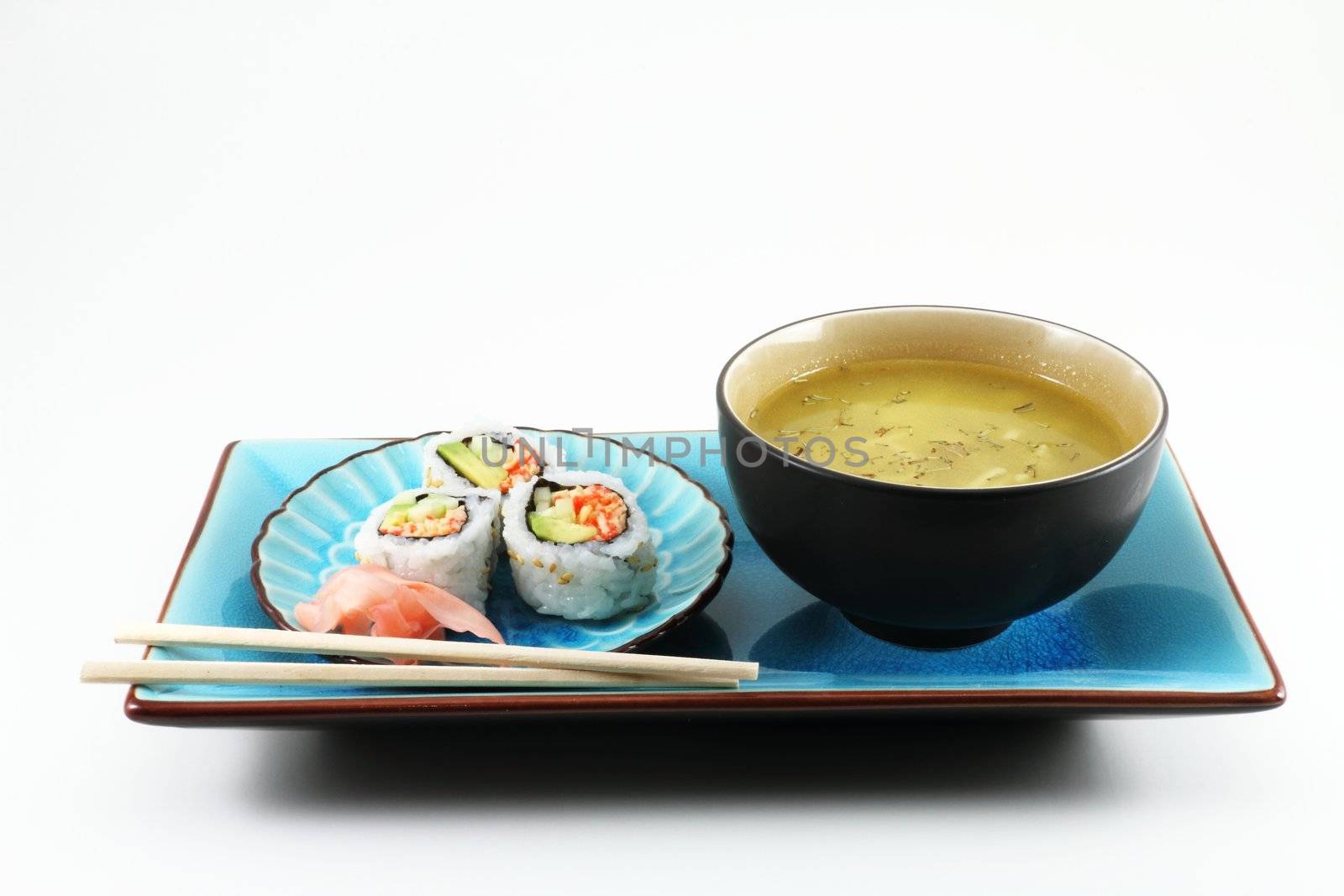 Sushi and soup on a blue plate with chop sticks.
