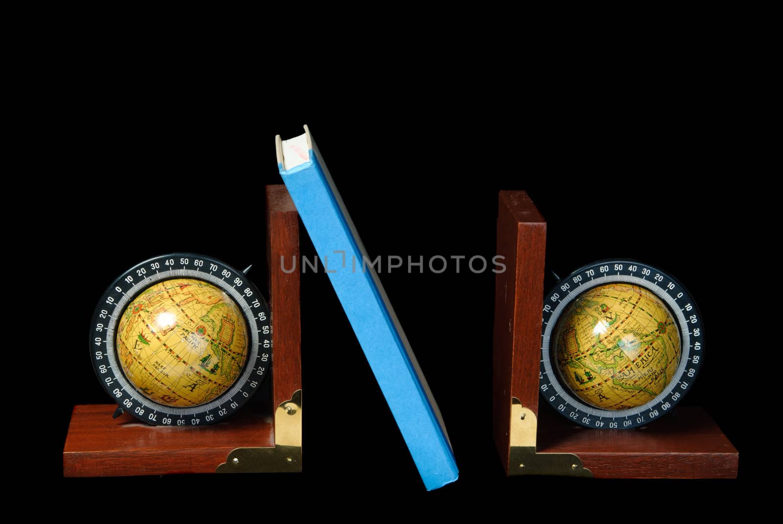 Two world globe bookends holding up a book, isolated against a black background