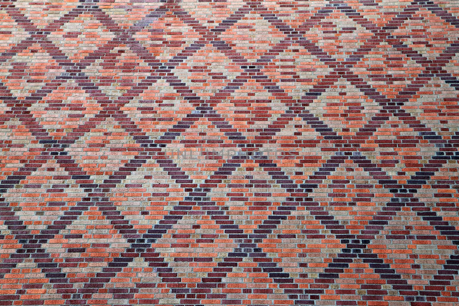 Large wall of various shades of red brick in a cross pattern