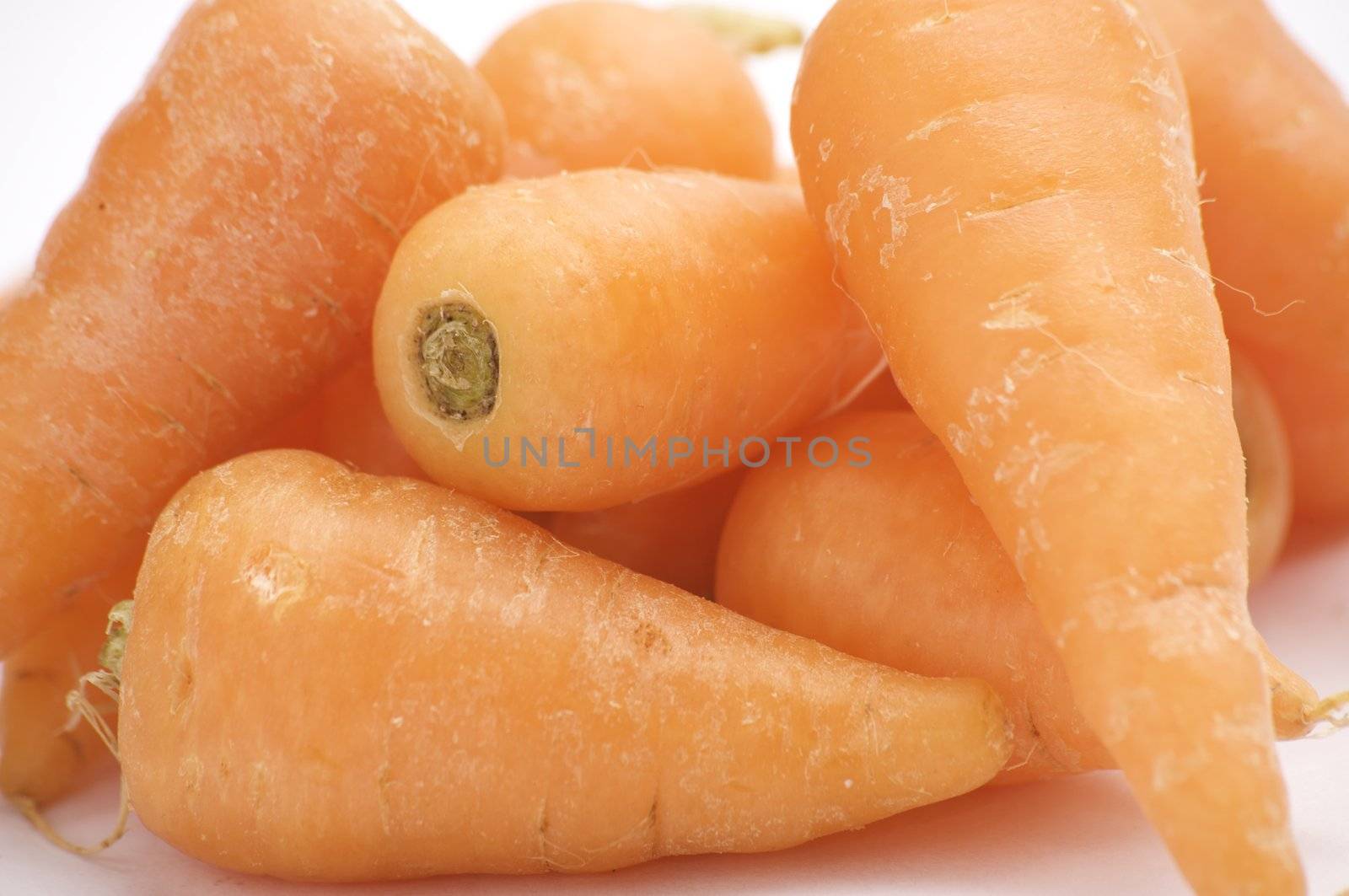 Fresh baby Carrots, isolated on a white background table, lit with a large light source from the above right.