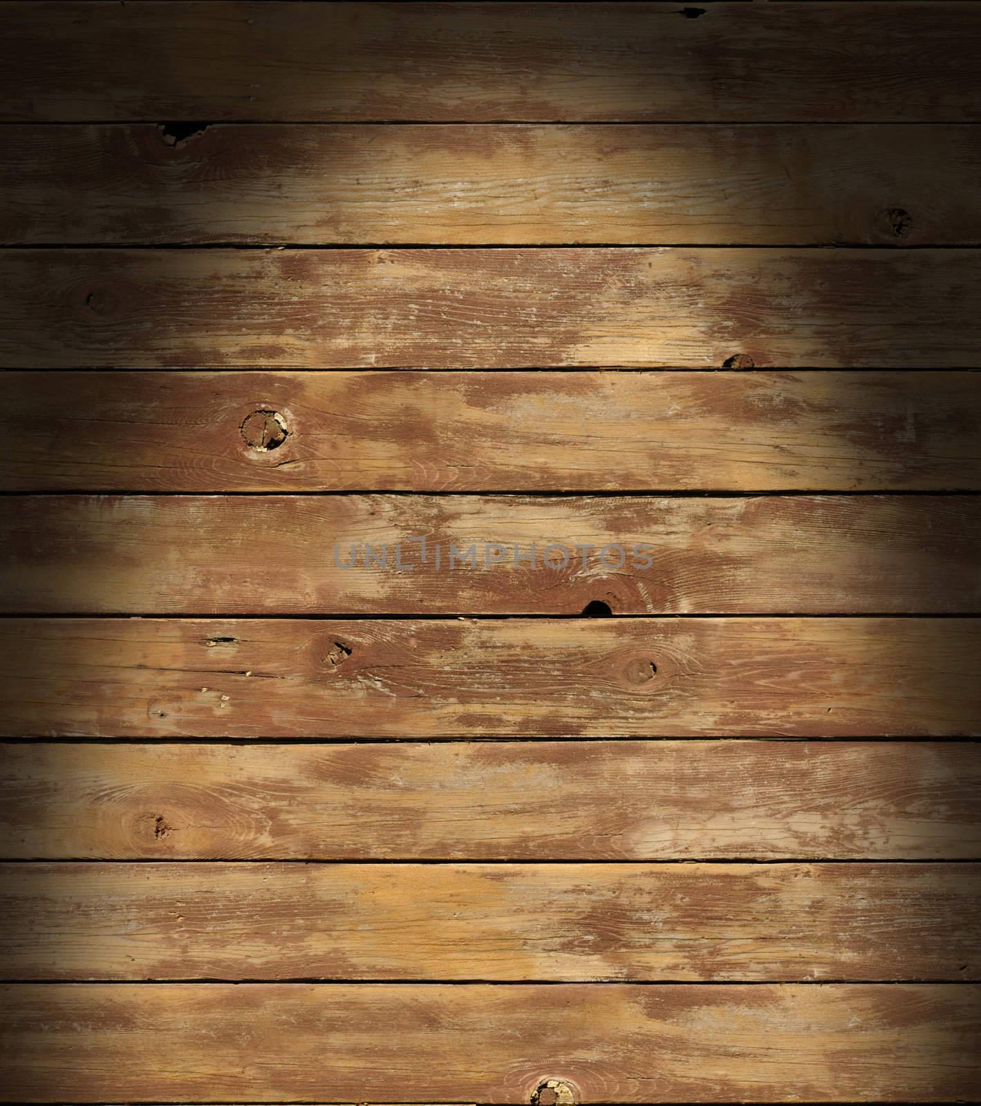 Distressed wooden surface lit dramatically from above with boards running horizontally.