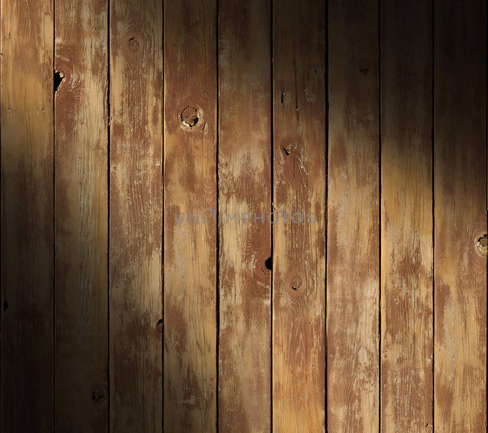 Distressed wooden surface diagonally lit with boards running vertically.