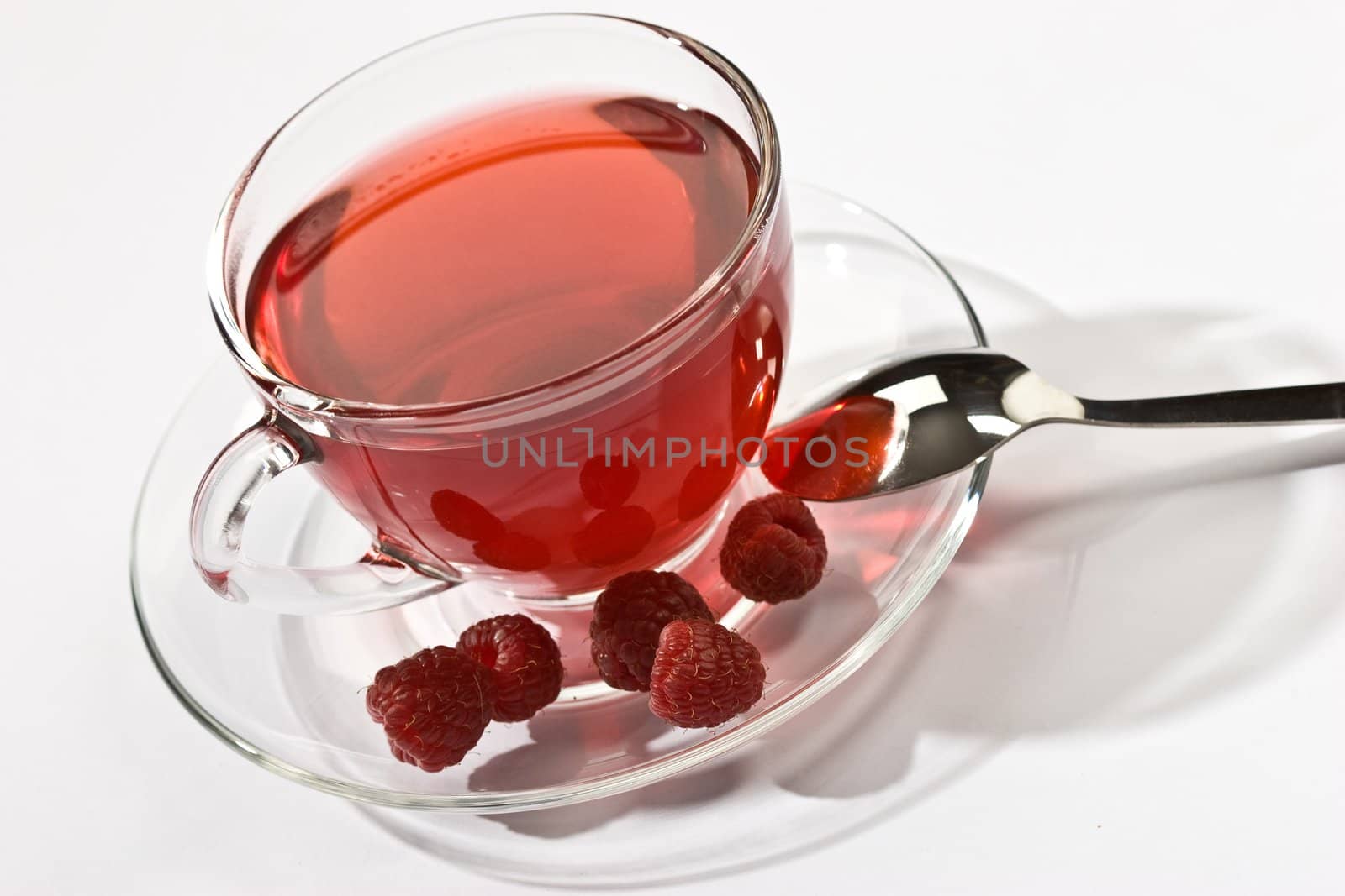 Cup of tea with raspberry syrup and some raspberries