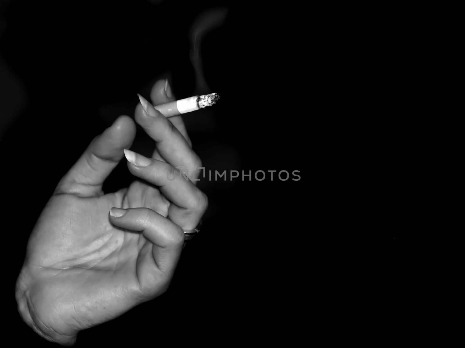 Female hand holding a burning cigarette in fingers