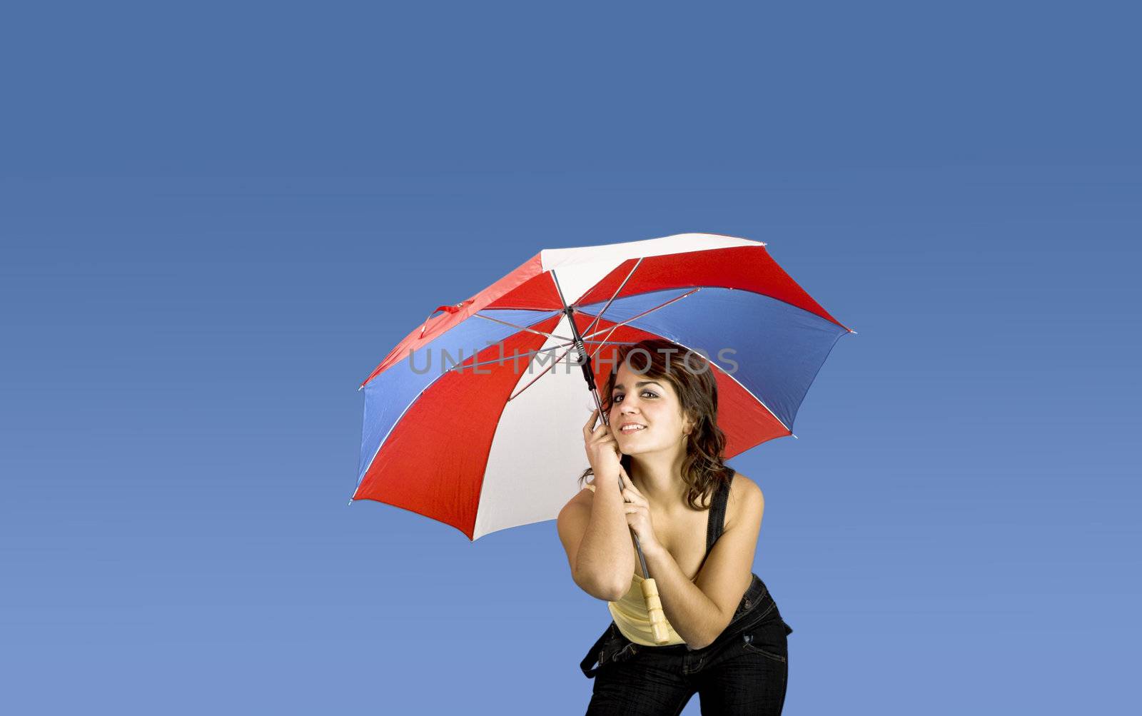 Portrait of a young happy woman posing with an umbrella on a blue background