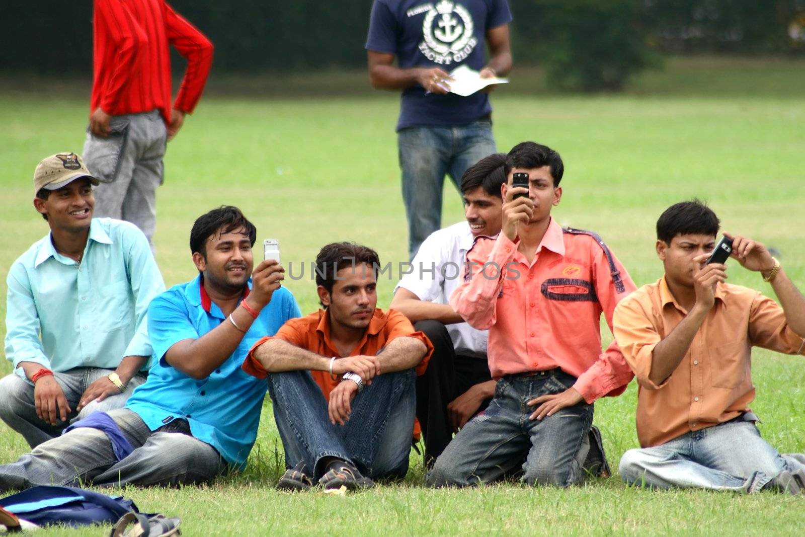 group of young men talking on the phone at the park