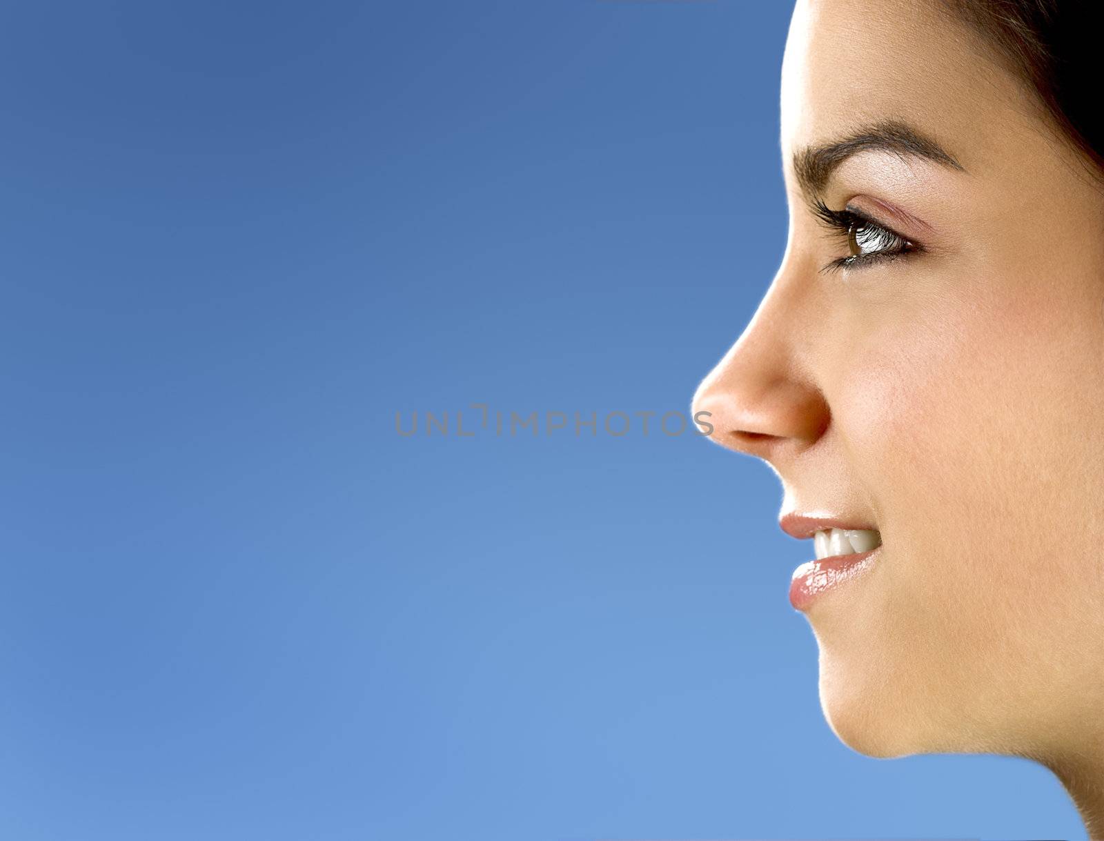 Profile portrait of a young and beautiful woman on a blue background