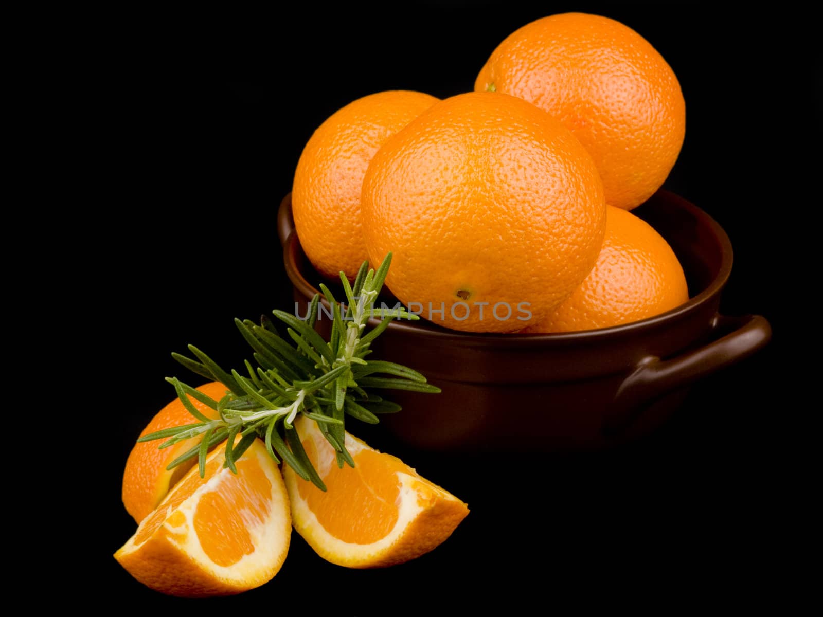 Oranges in ceramic bowl on black background