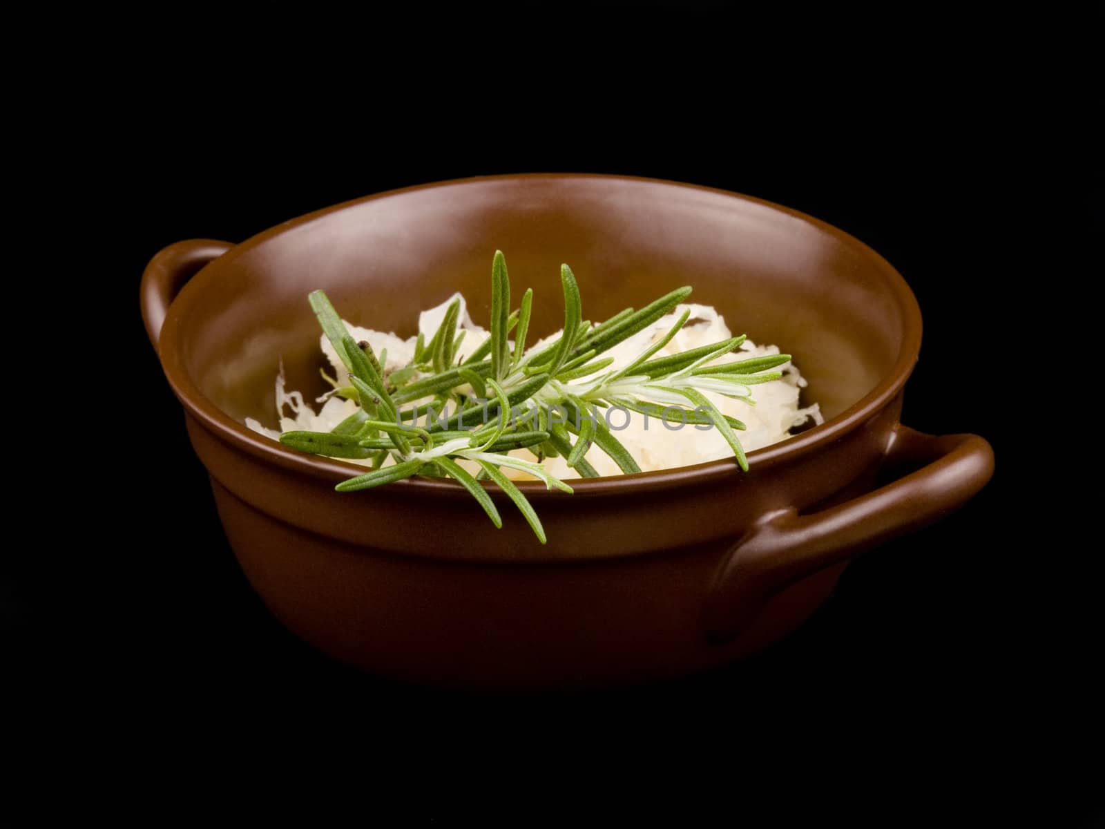 Ceramic bowl filled with sour cabbage on black background