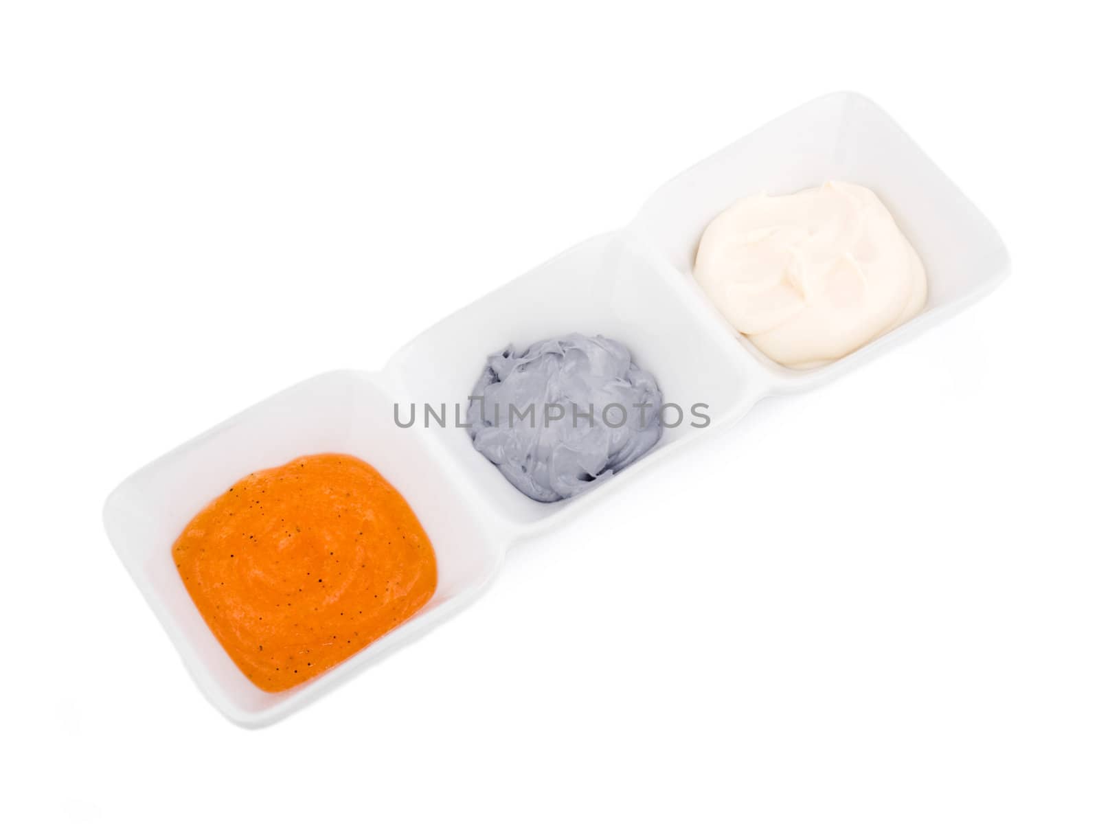 Orange peeling, grey mask and white cream in porcelain bowls on white background.