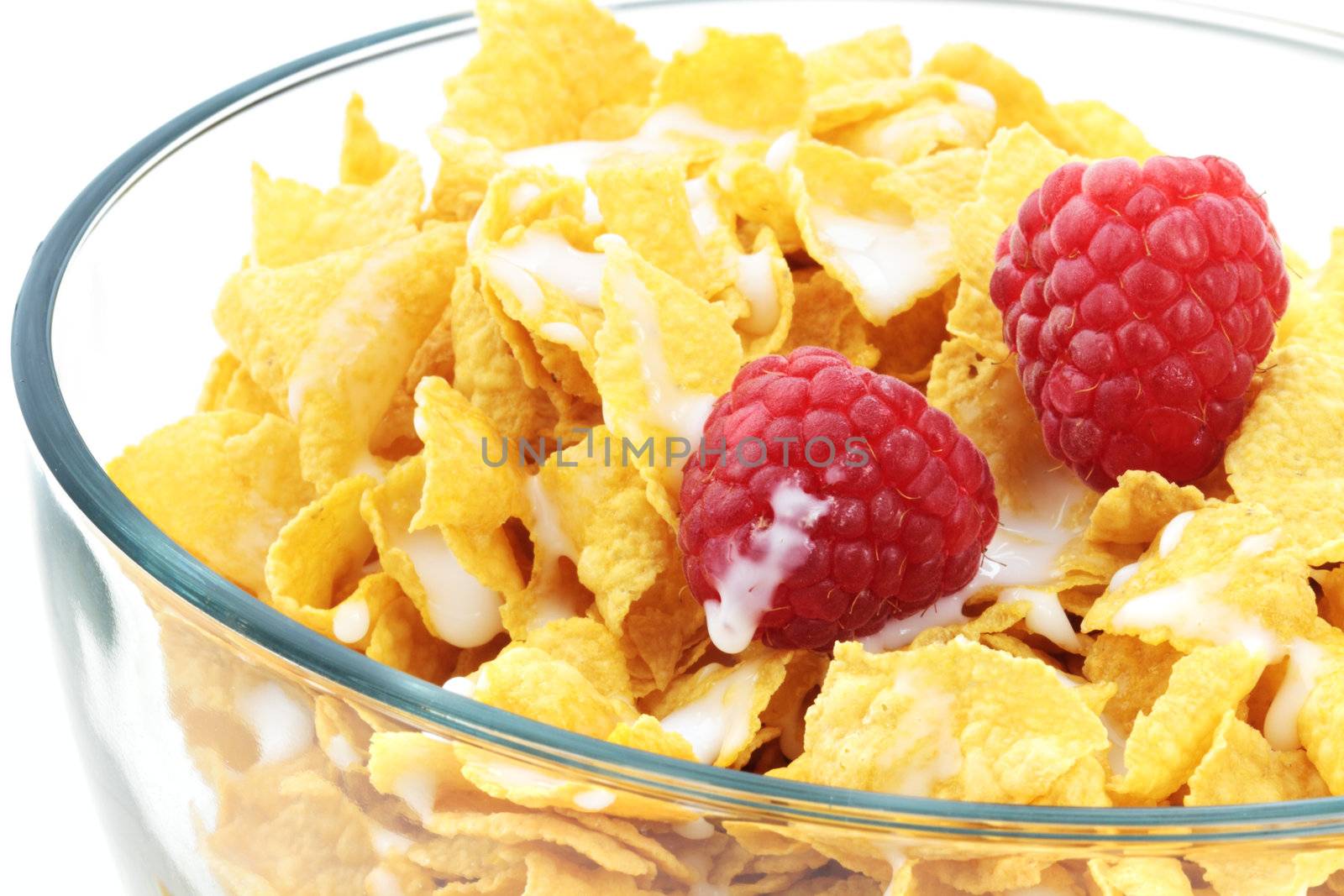 Cereal with milk and fresh raspberries in a clear bowl isolated on white.