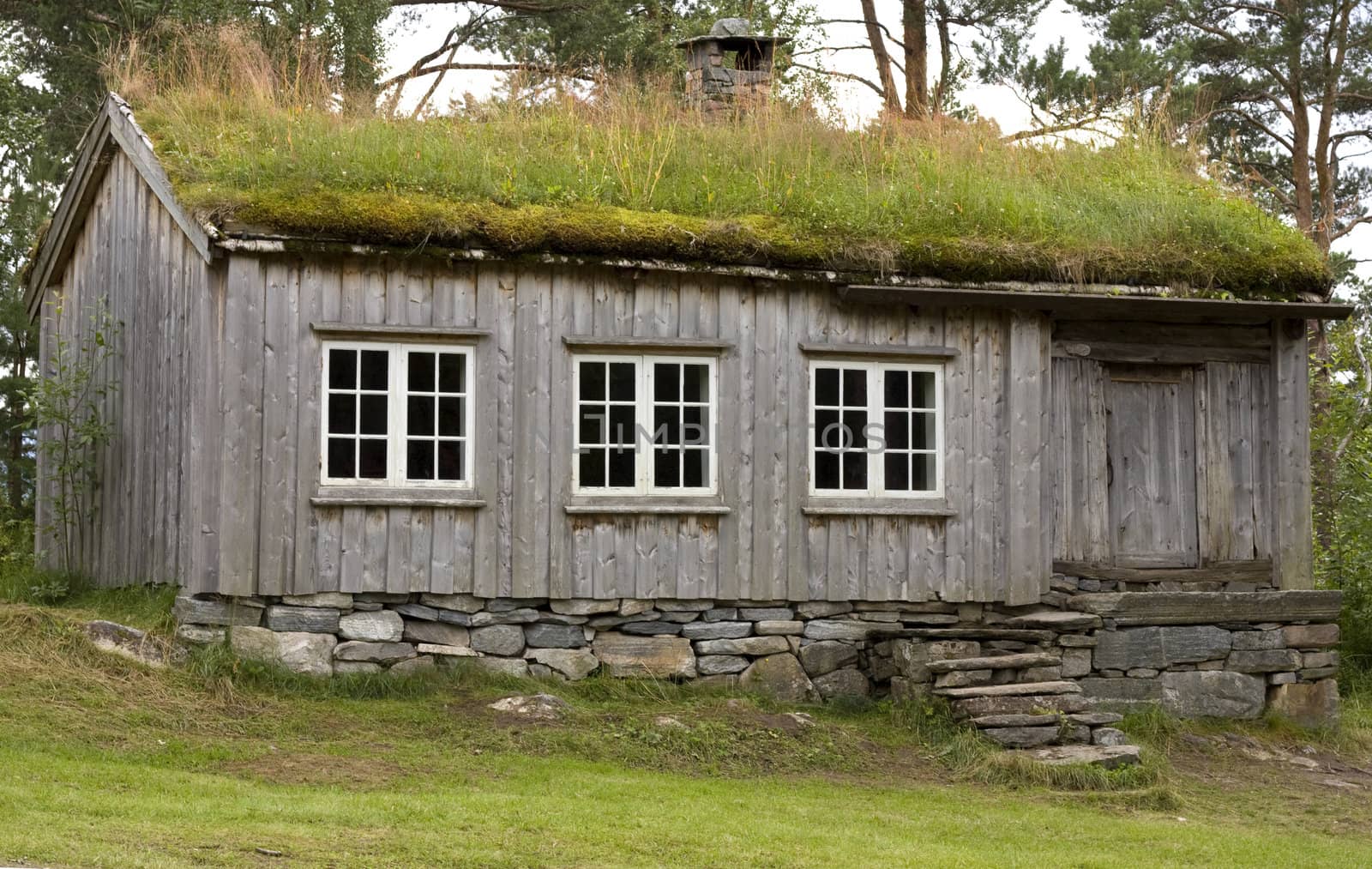 Old wooden mountain cabin with turf roof