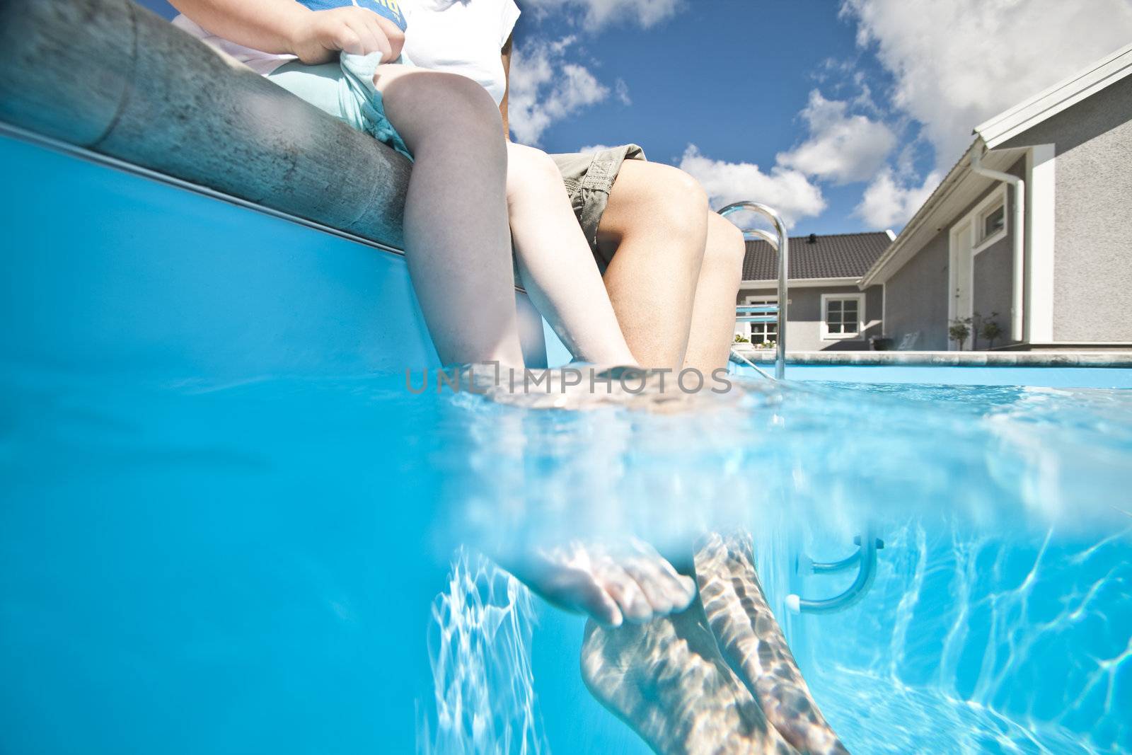 Mother and daughter with their feet in the swimming pool