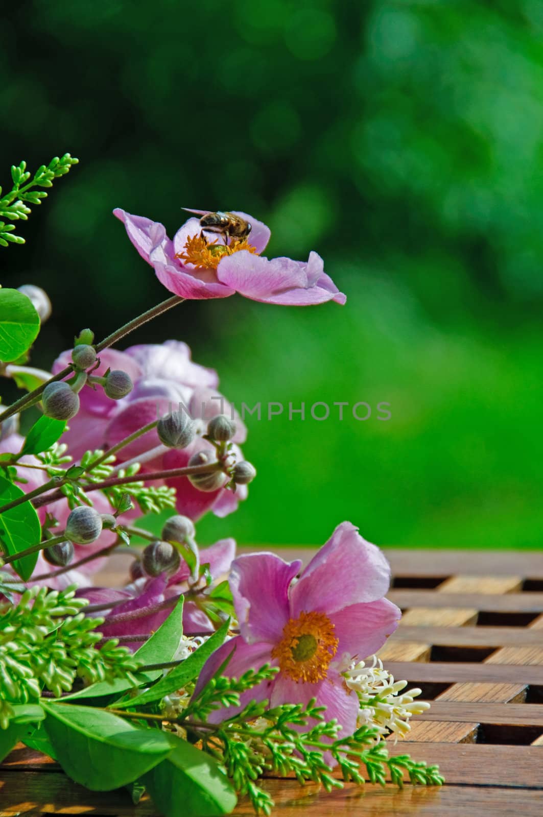 A bouquet of flowers lying on a garden table with a buzzing bee