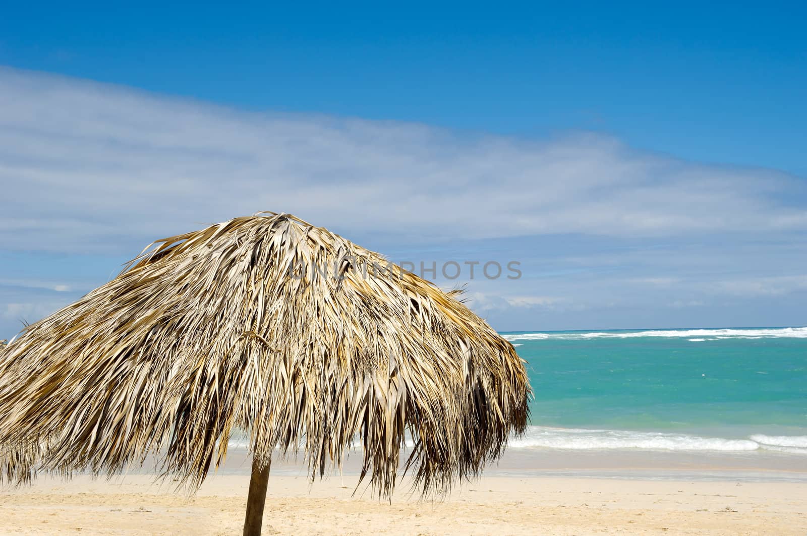 Parasol made out of palm leafs on beach.