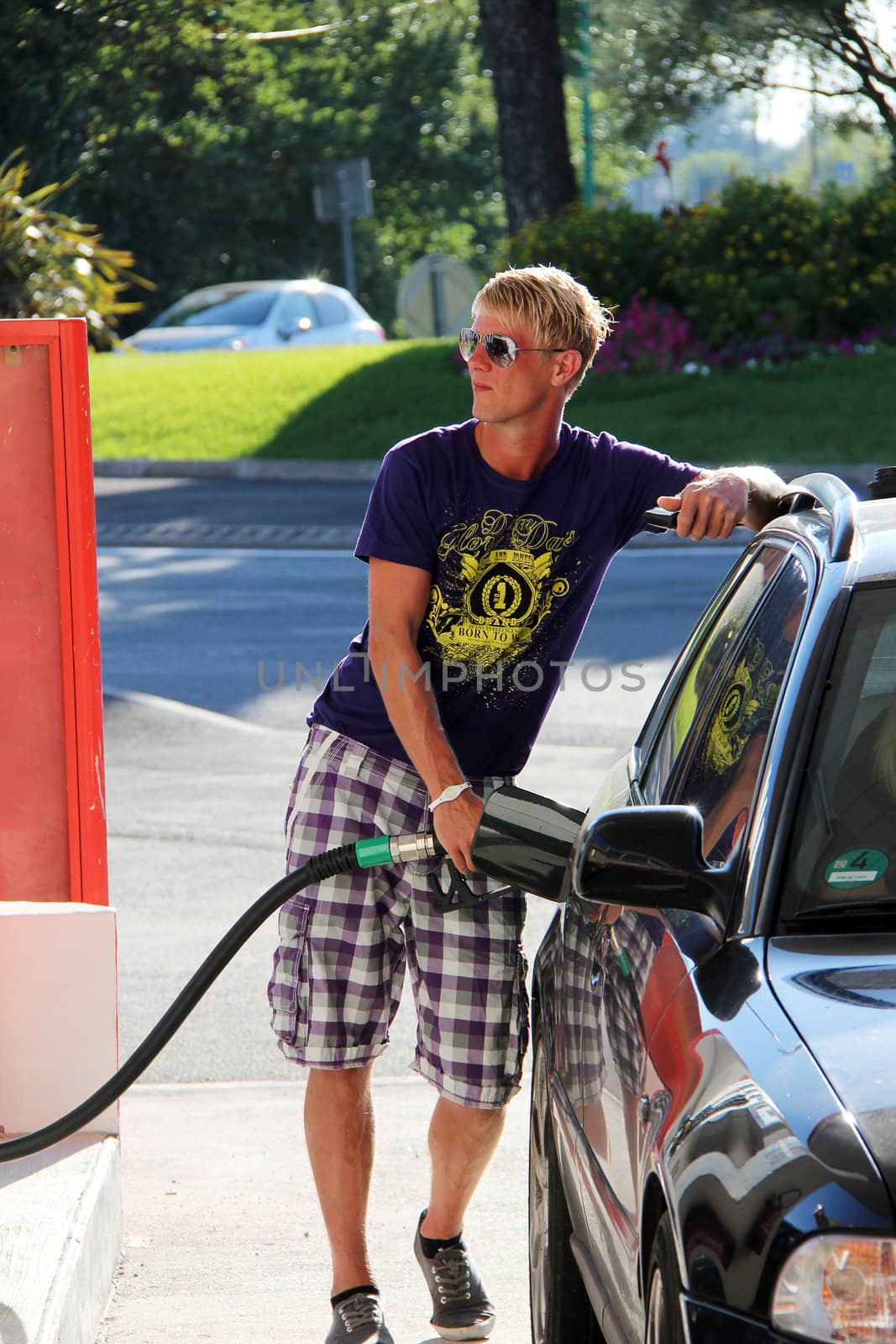 young blonde boy with sunglasses is getting fuel