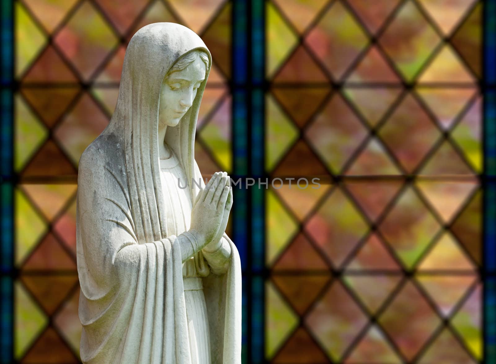 Statue of Mary praying in profile with isolation path and out of focus window as background
