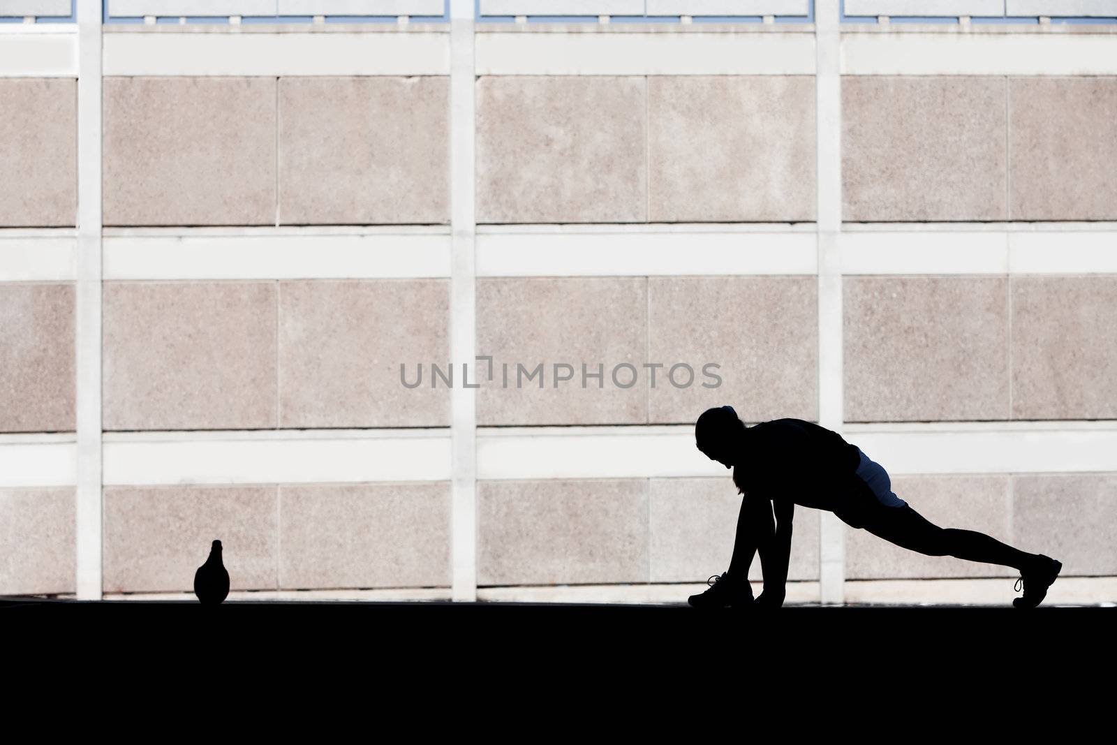 Female runner stretches in the morning. by Creatista