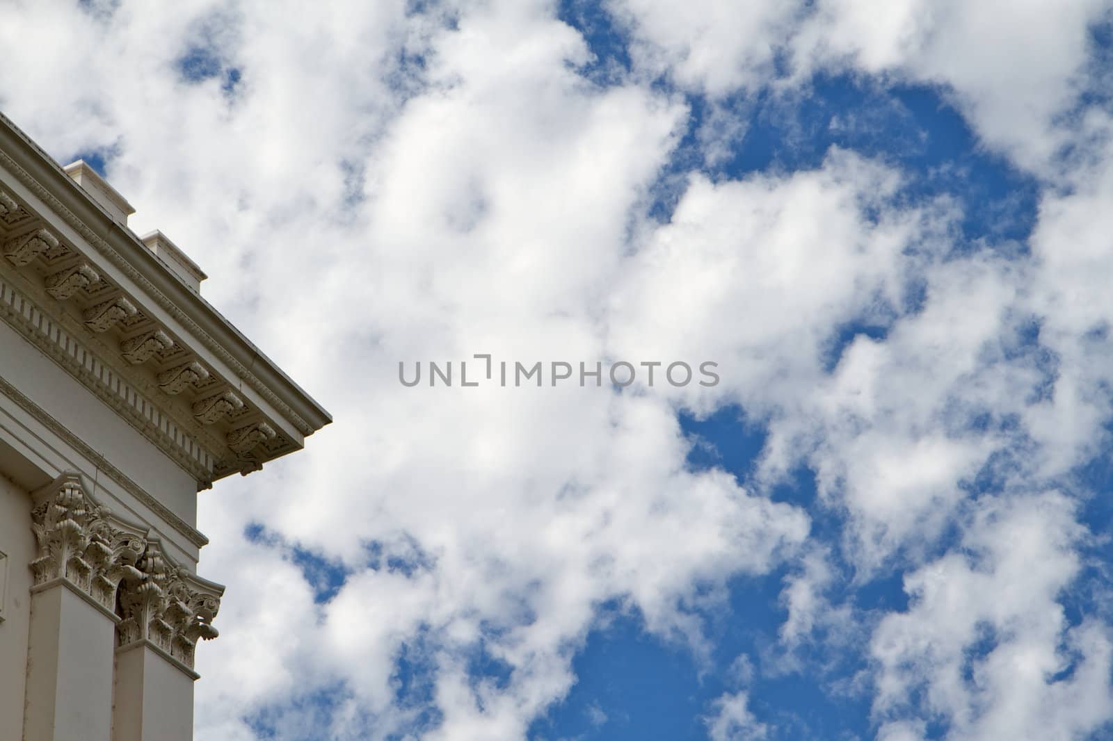 Corner of California Capitol building against blue sky with puffy Sky