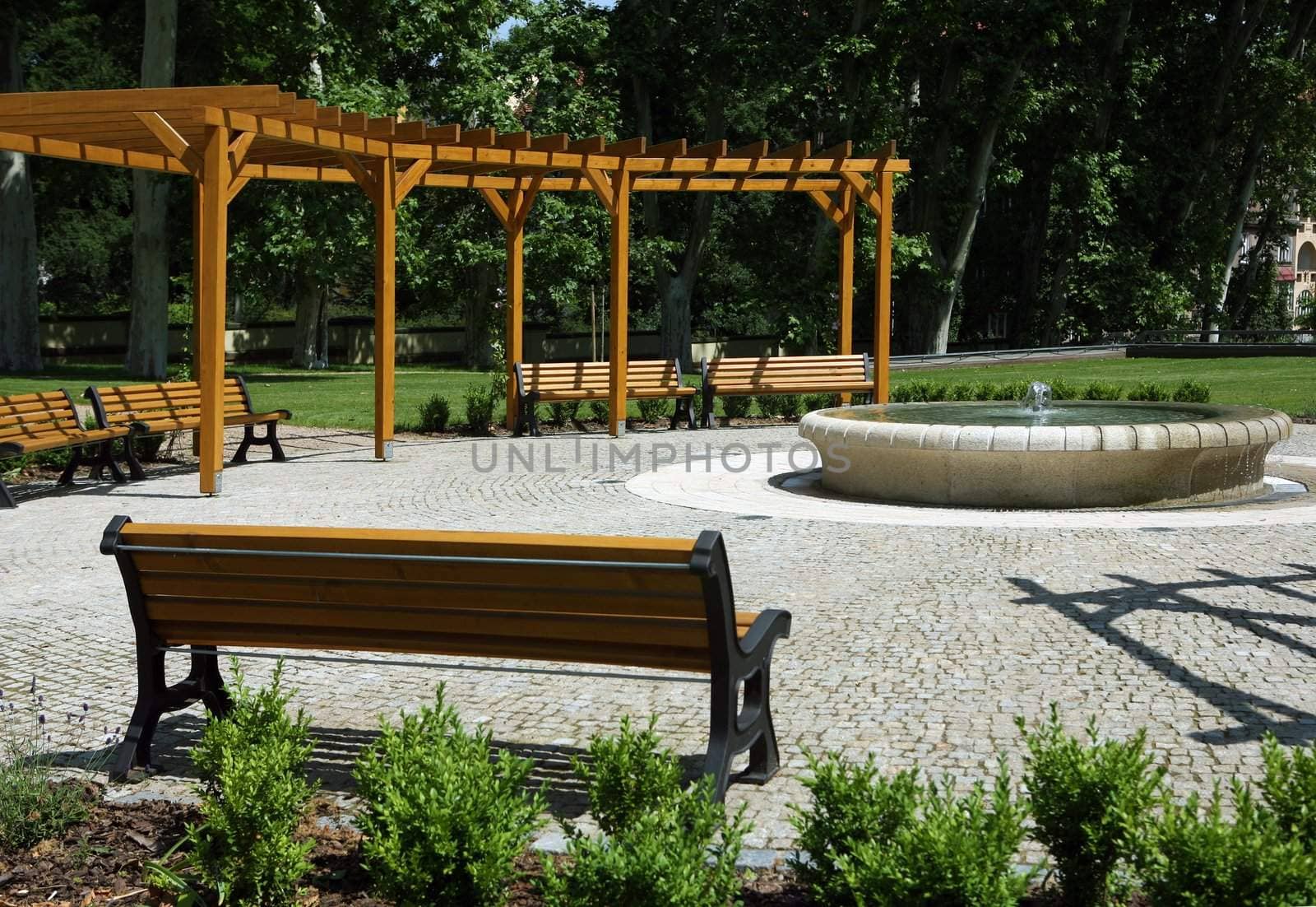 Park with fountain, benches, and wooden construction around