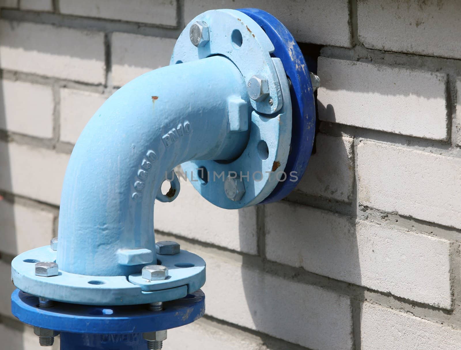 Blue painted pipe on the white bricks wall