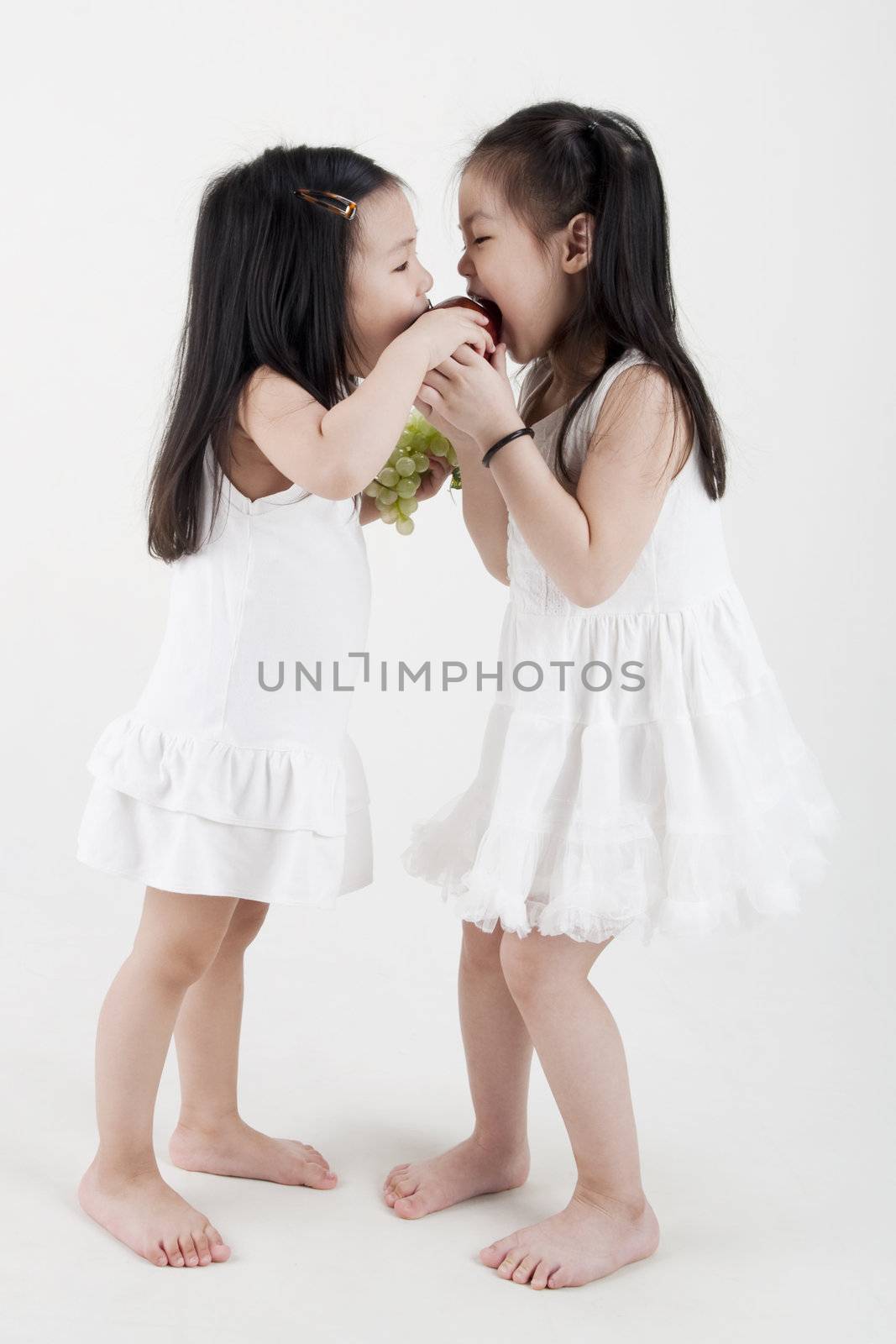 Two little girls sharing an apple