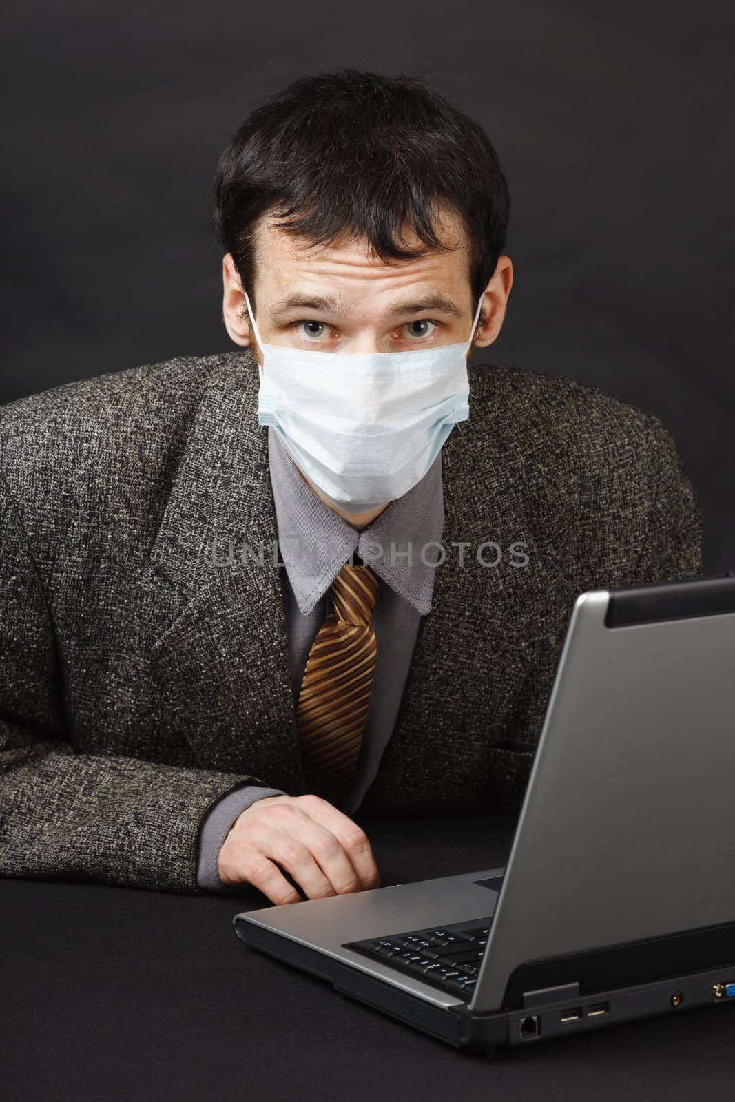 The young man in a medical mask works in the Internet