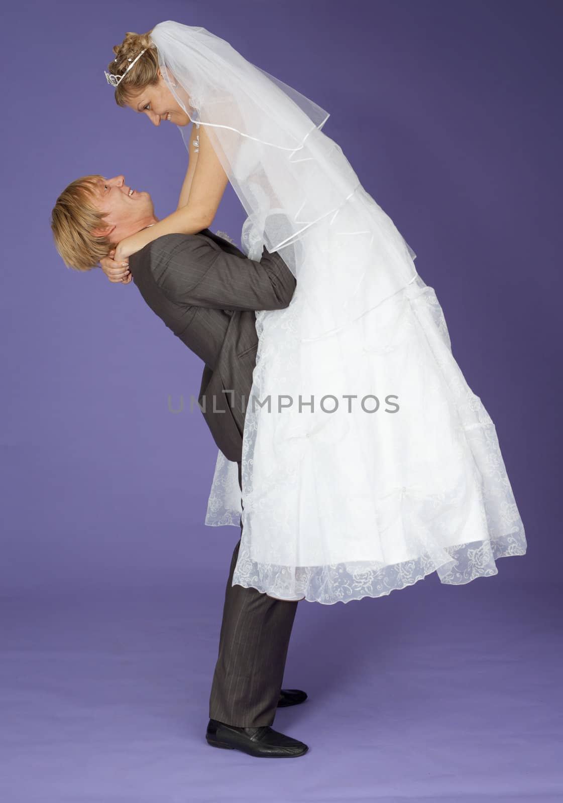 Strong groom holds admired bride on hands by pzaxe