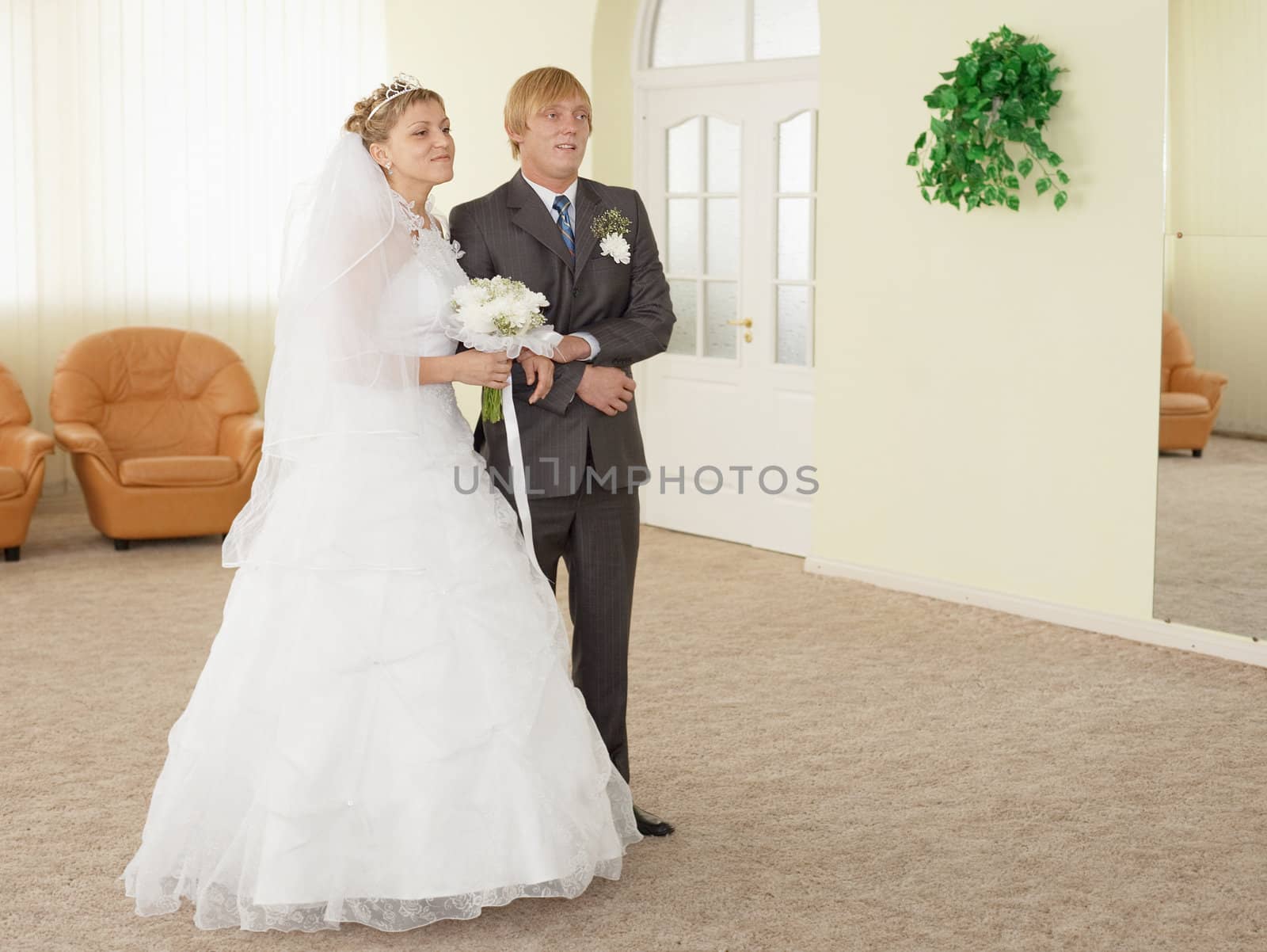 The groom with the bride in a ceremonial hall during wedding