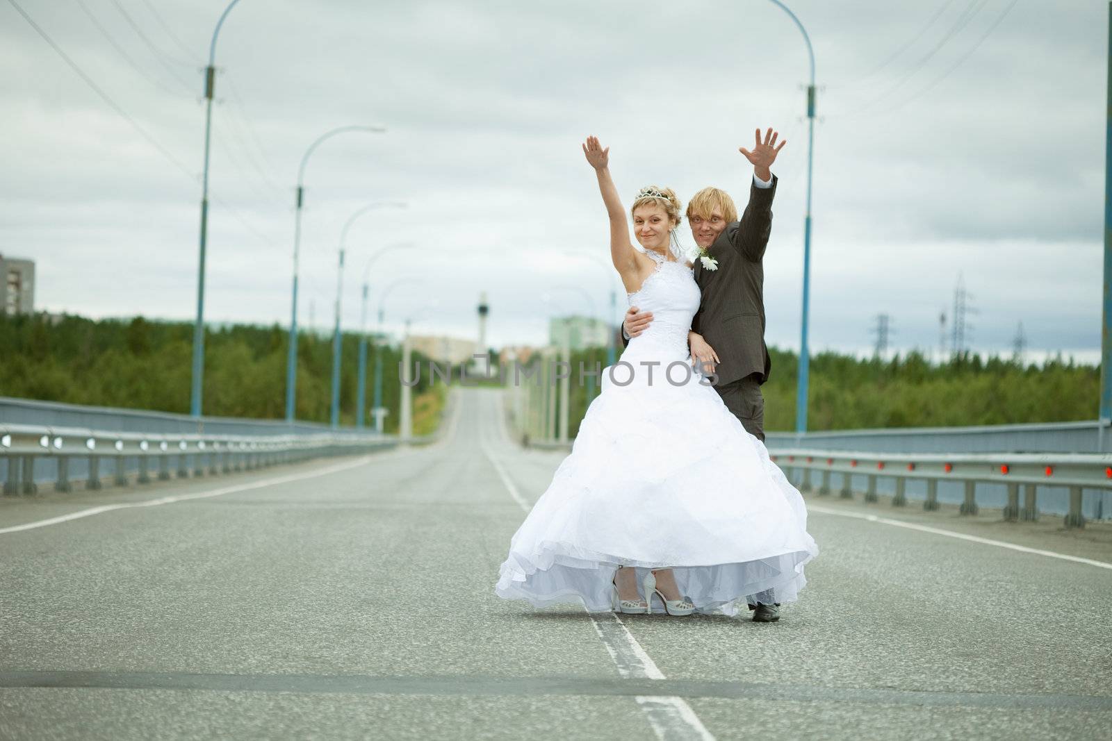 Newly married have fun standing on country highway