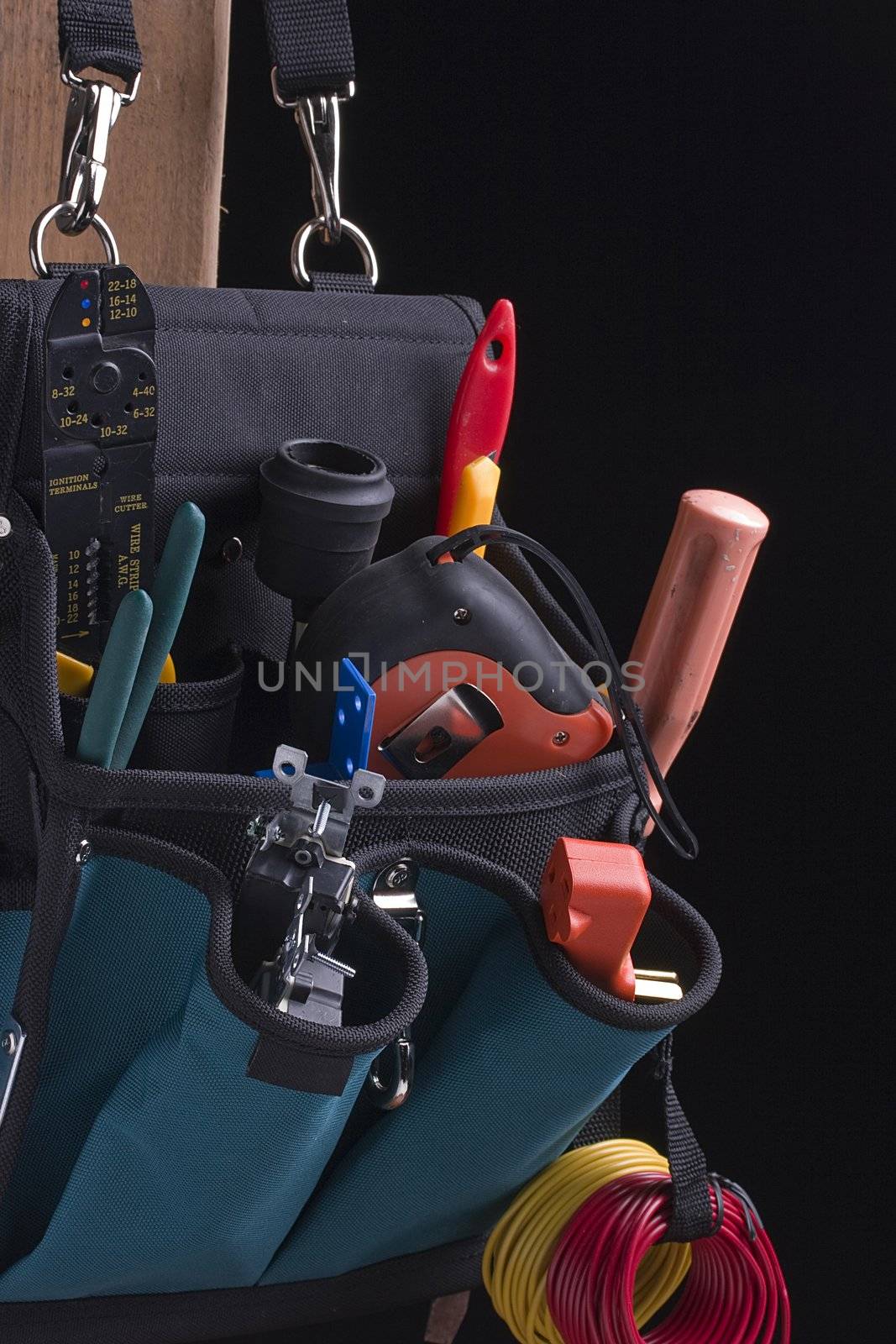 Electrician's bag with tools on a black background.