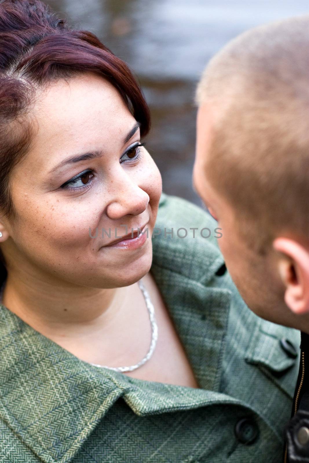 A young happy couple looking at one another outdoors. Shallow depth of field with focus on the woman.