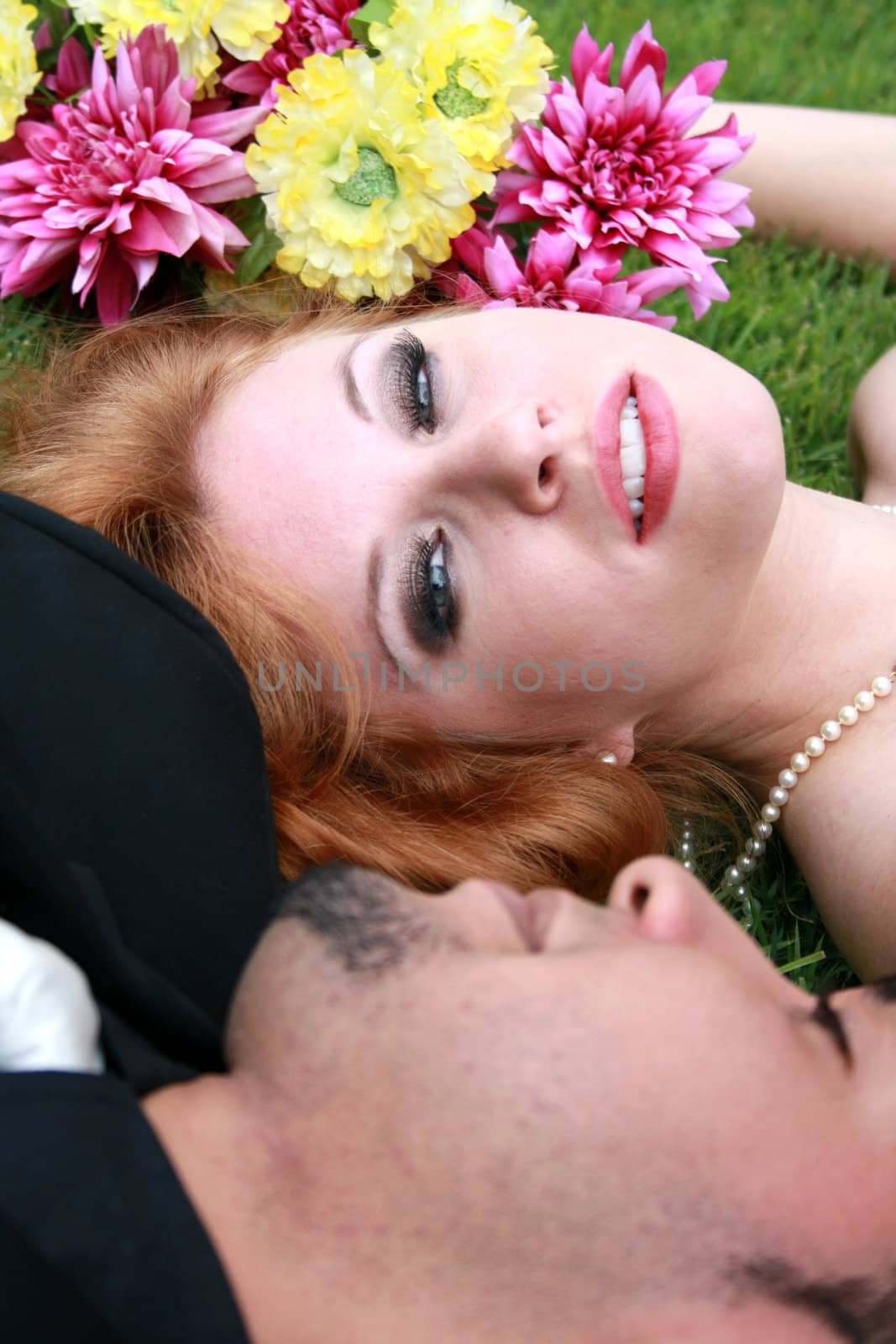 Bride and Groom lying on grass by mahnken