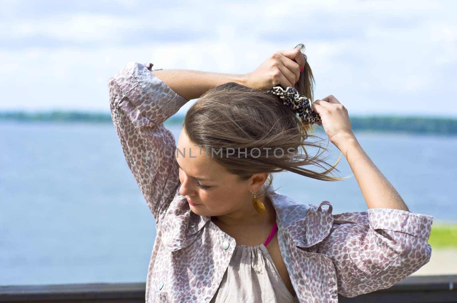 Young beautiful girl tying her hair hairpins. Summer portrait. Blurred background.