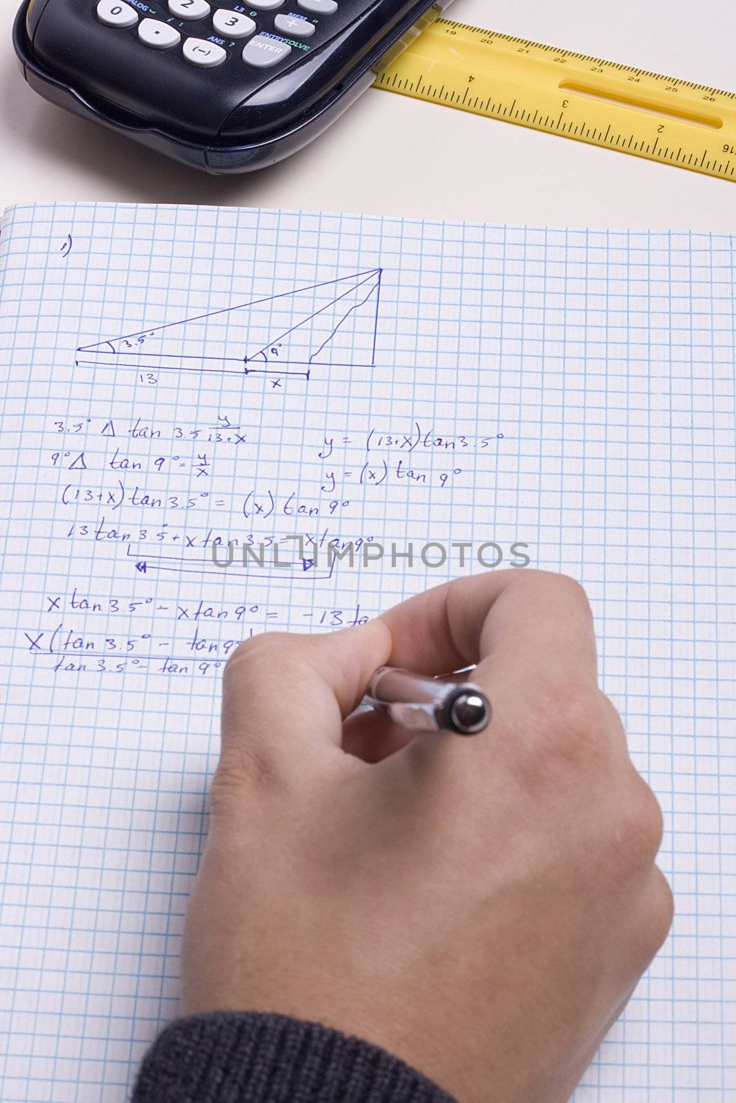 Student writing a math exam in a notebook.