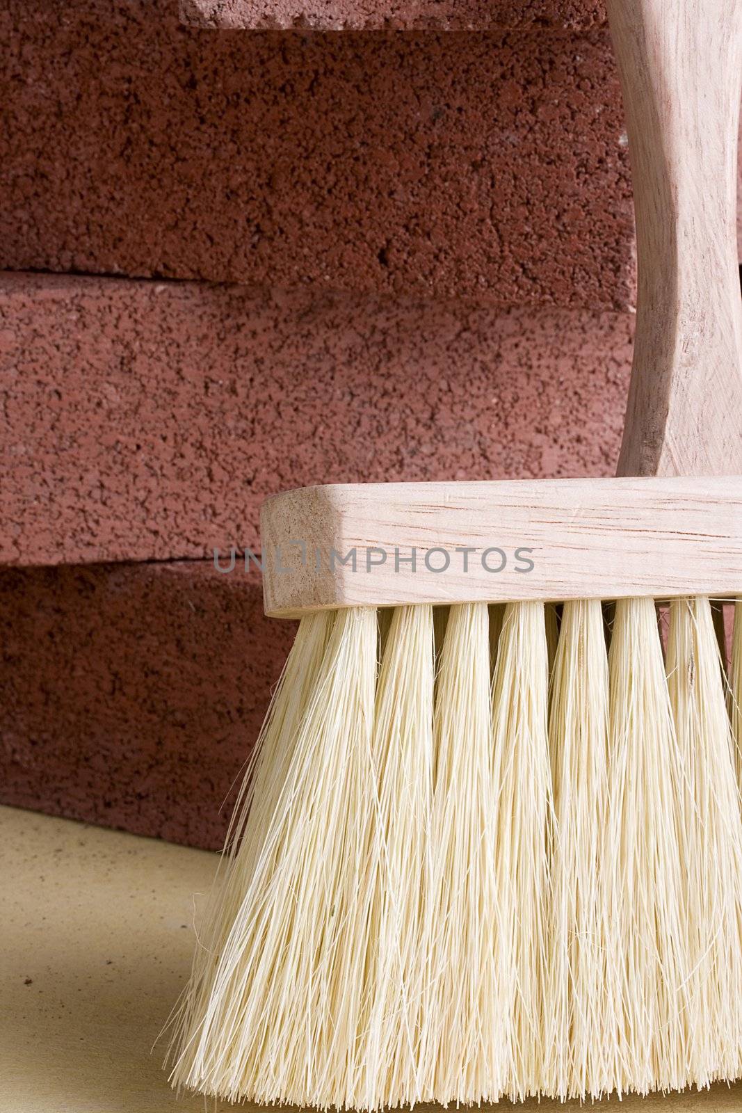 Stonemason's brush next to a stack of red bricks.