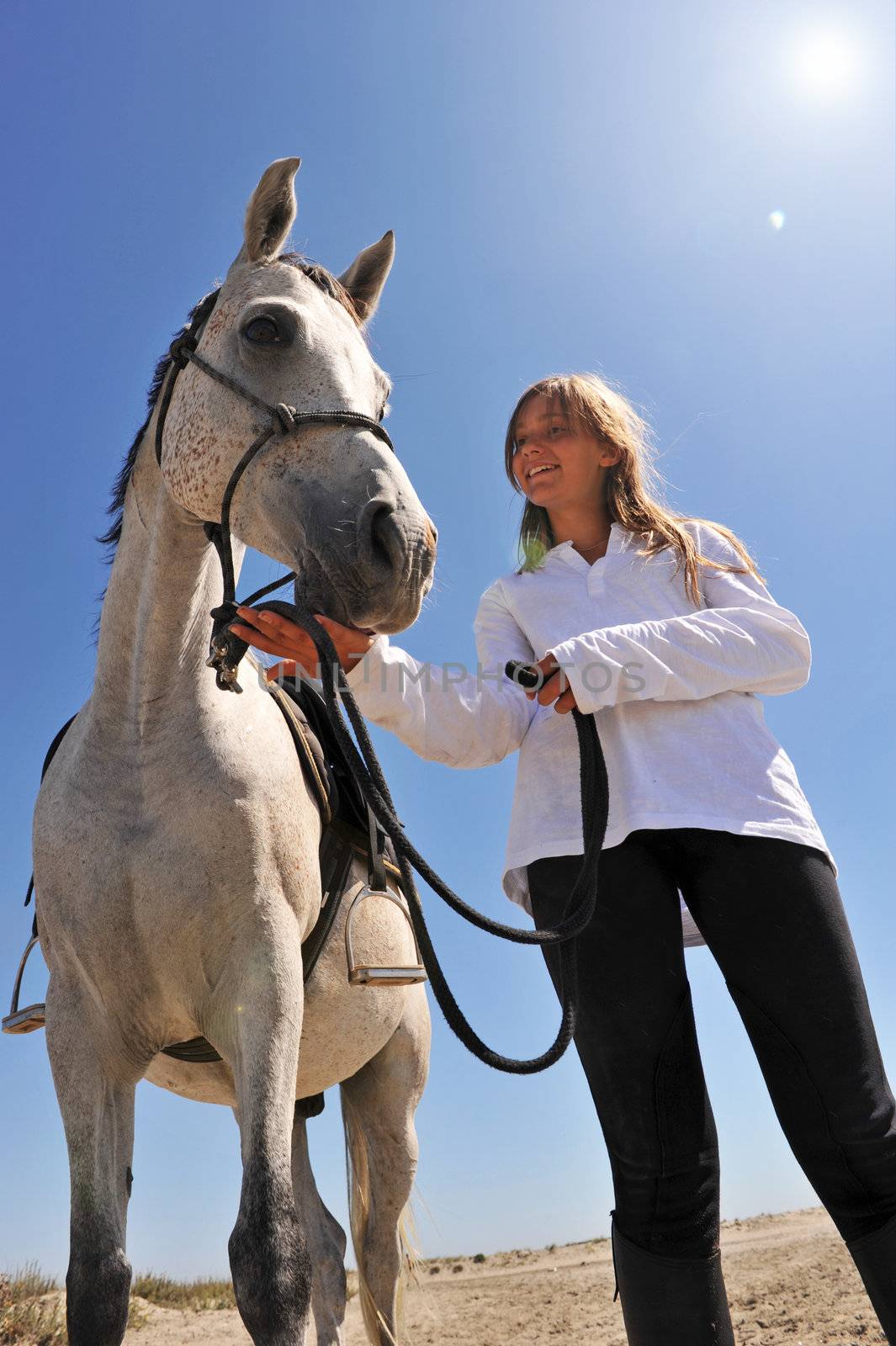 smiling young teen and her gray arabian horse on the beach