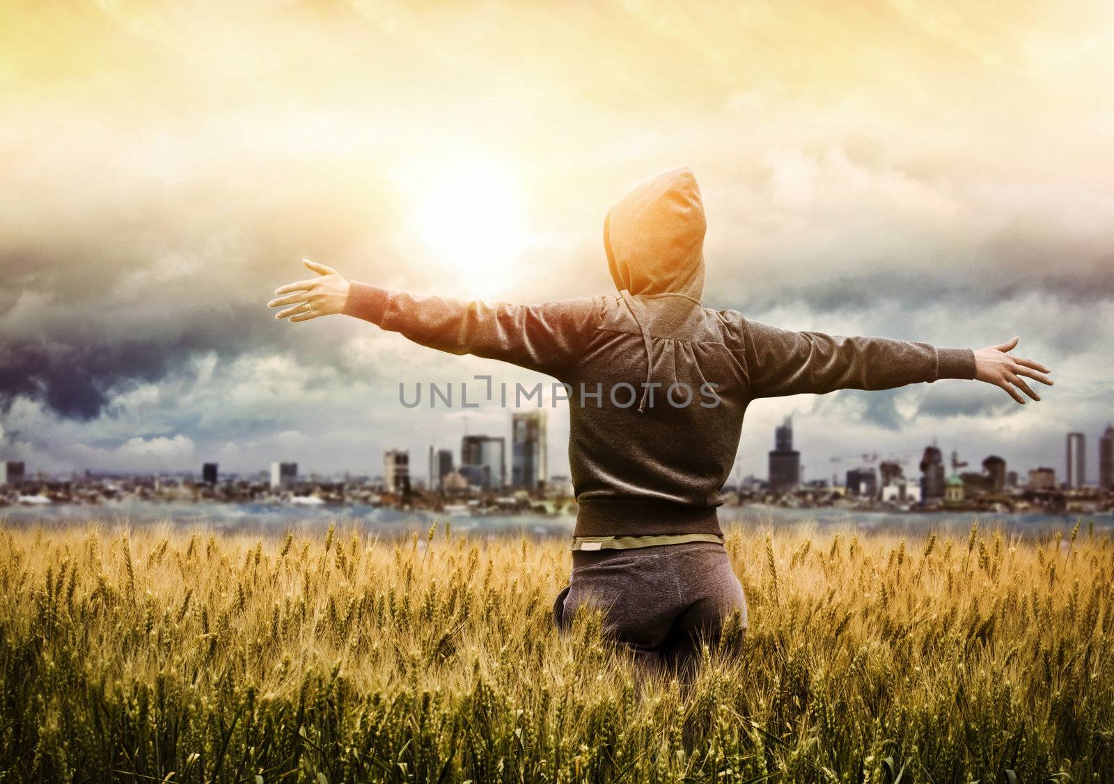 Young women in wheat field looking at sunset