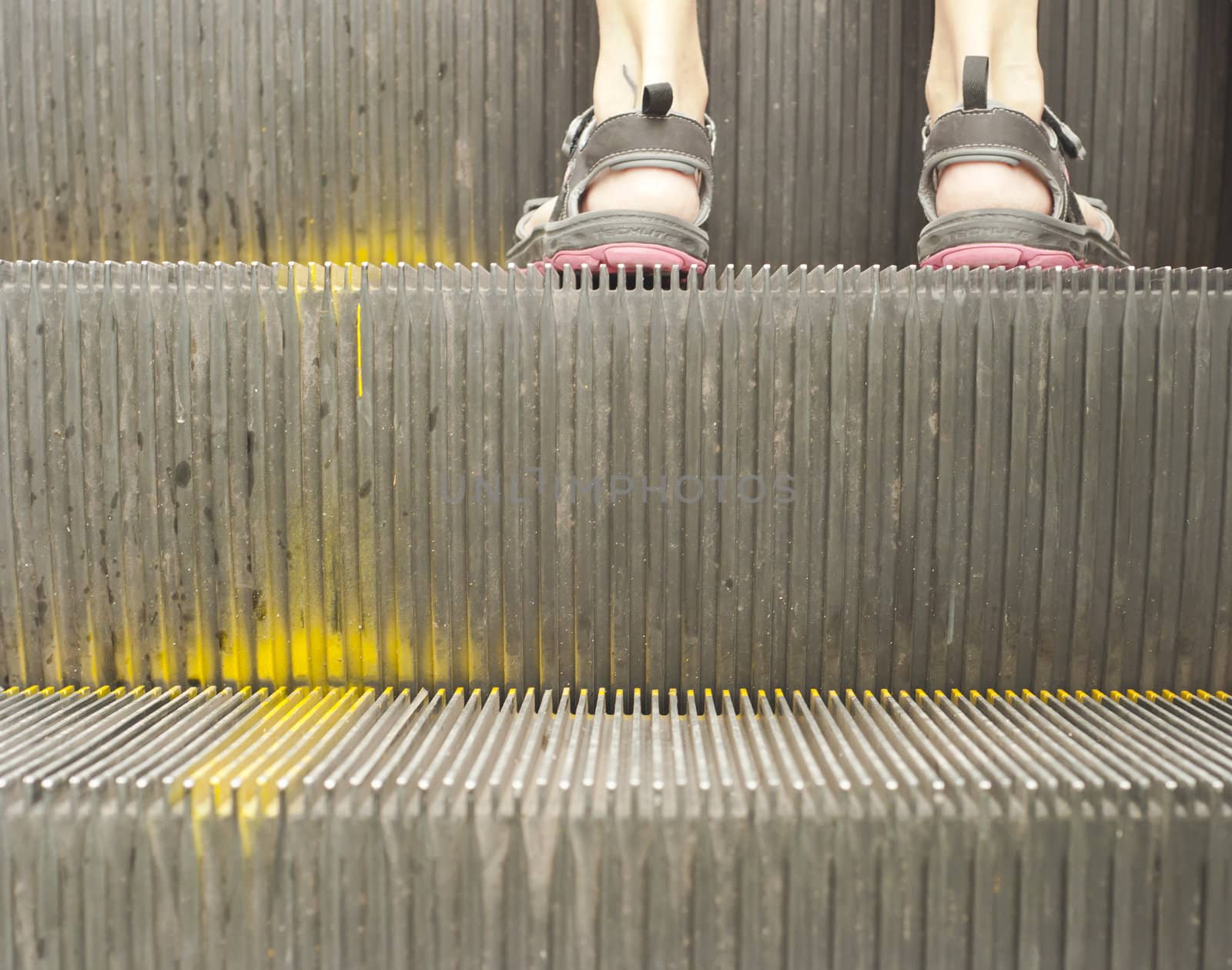 Two feet of a female traveller on an old escalator