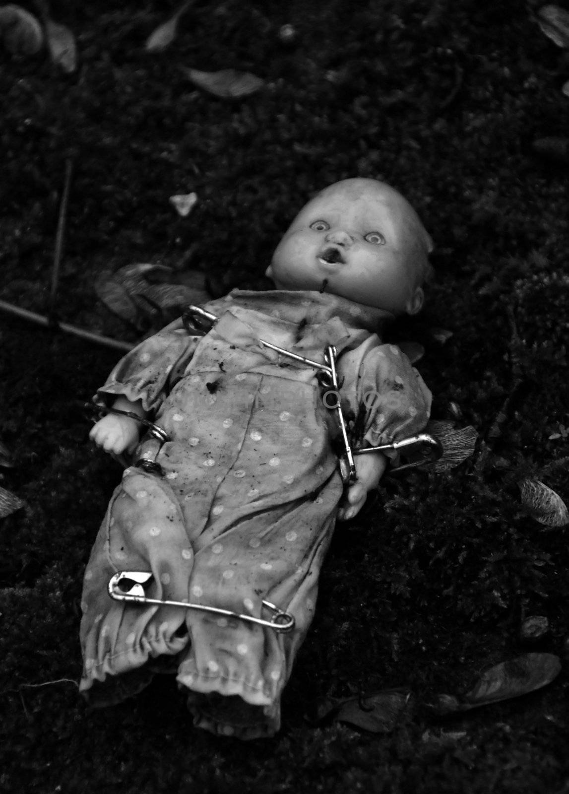 an abandonned doll with pins on a tomb in a cimetarry
