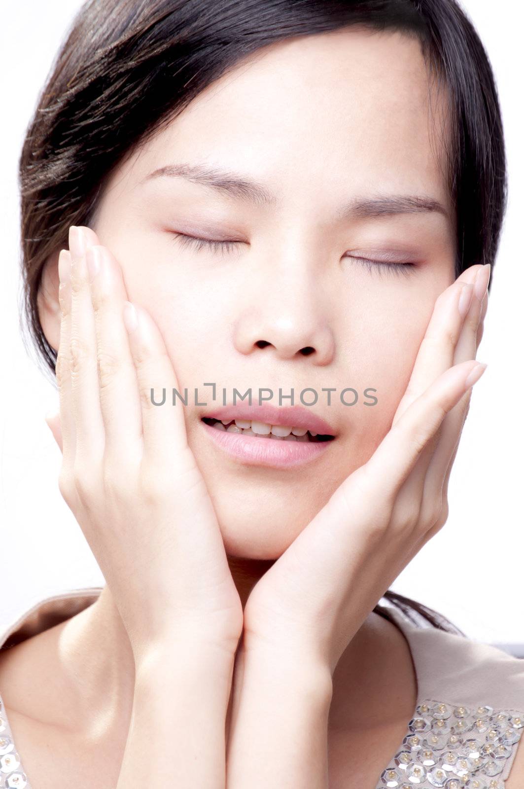 Young asian female with her hands on face in beauty shot