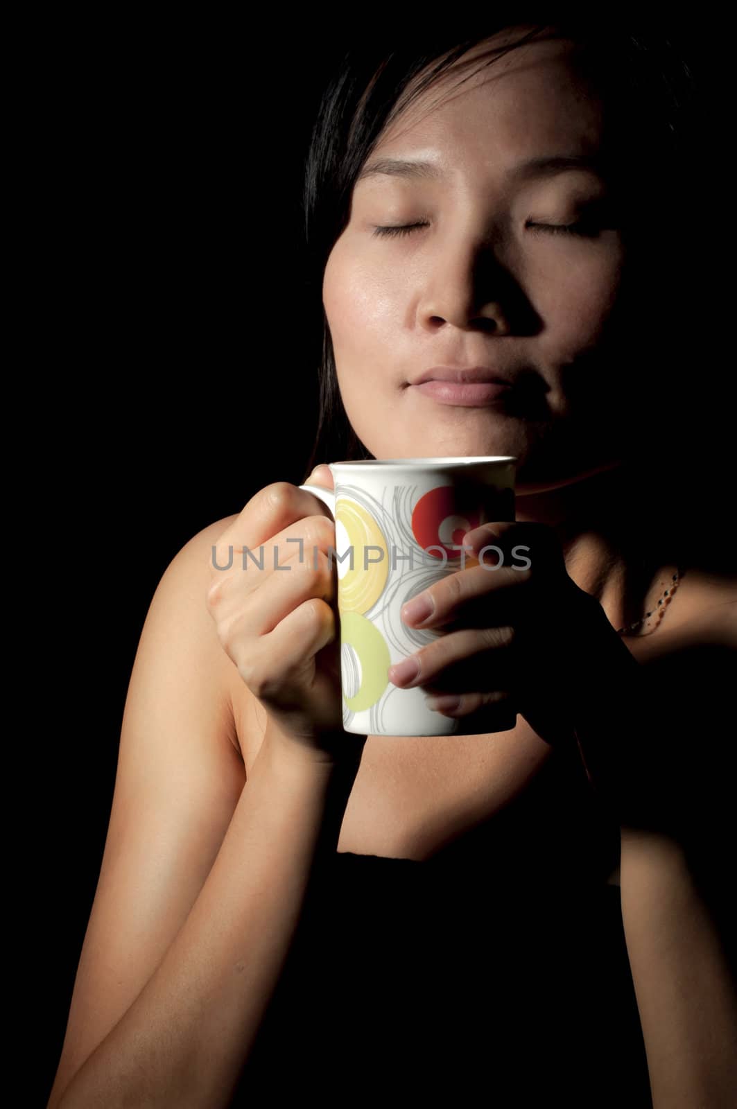 Attractive woman  with an aromatic coffee in hands isolated on black background