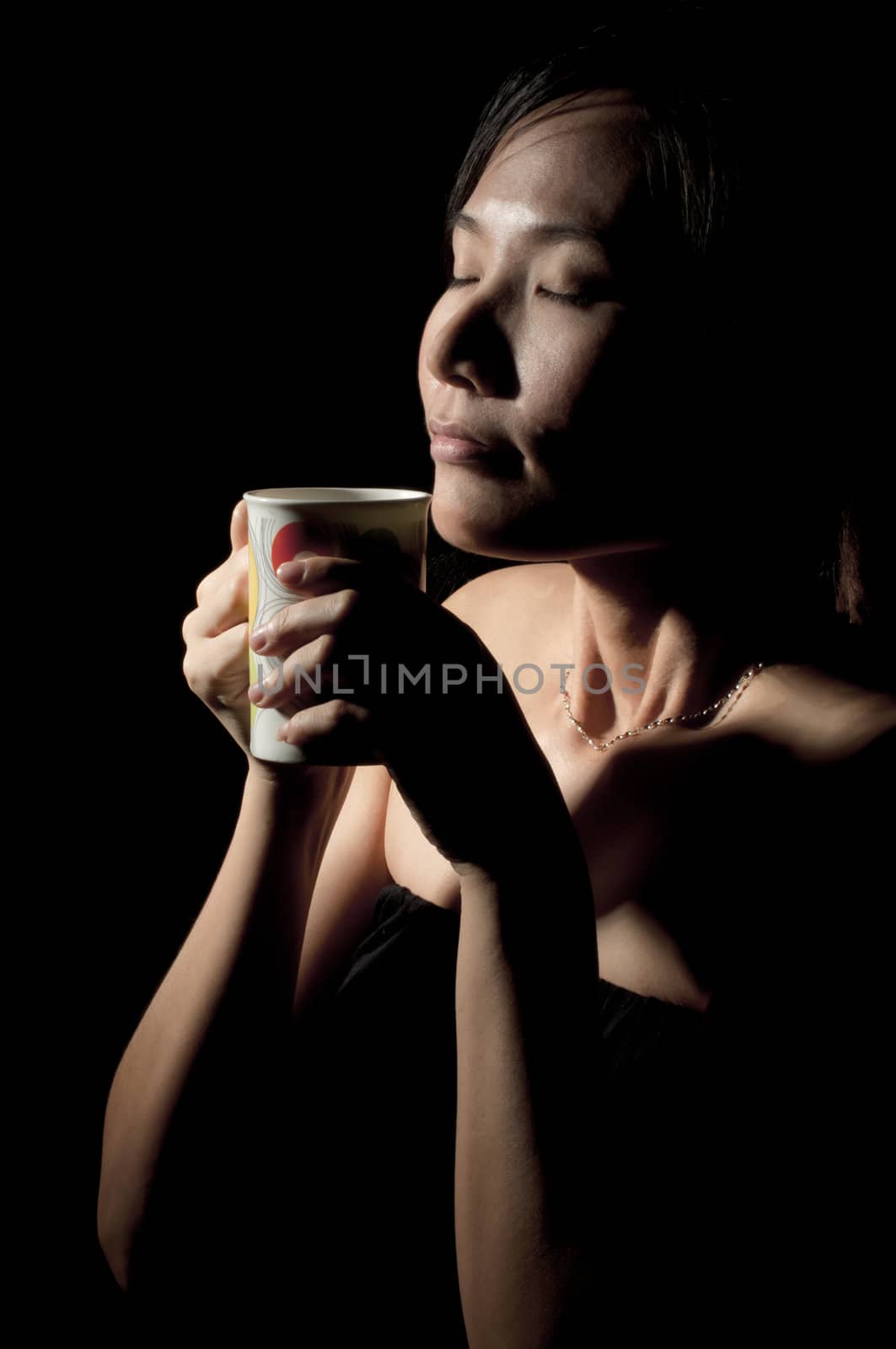 Attractive woman  with an aromatic coffee in hands isolated on black background