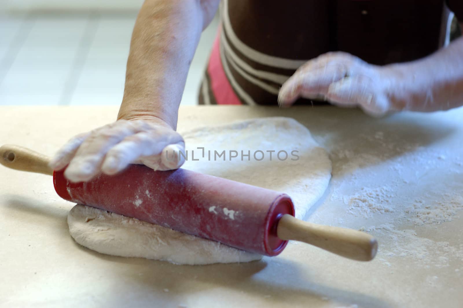 elderly woman using rolling pin on pizza dough   
