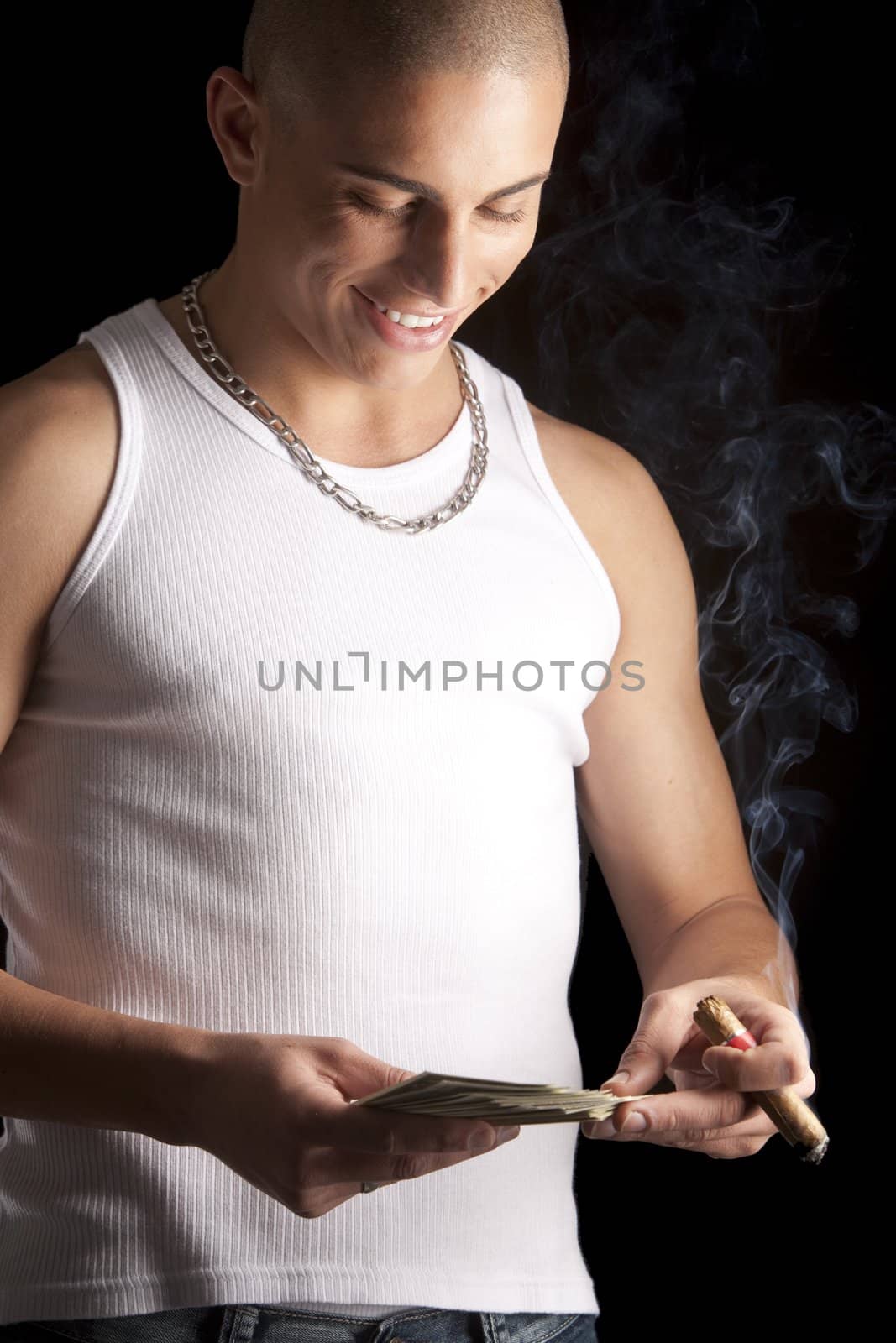 A good looking, muscular built, man on a black background smoking cigar.