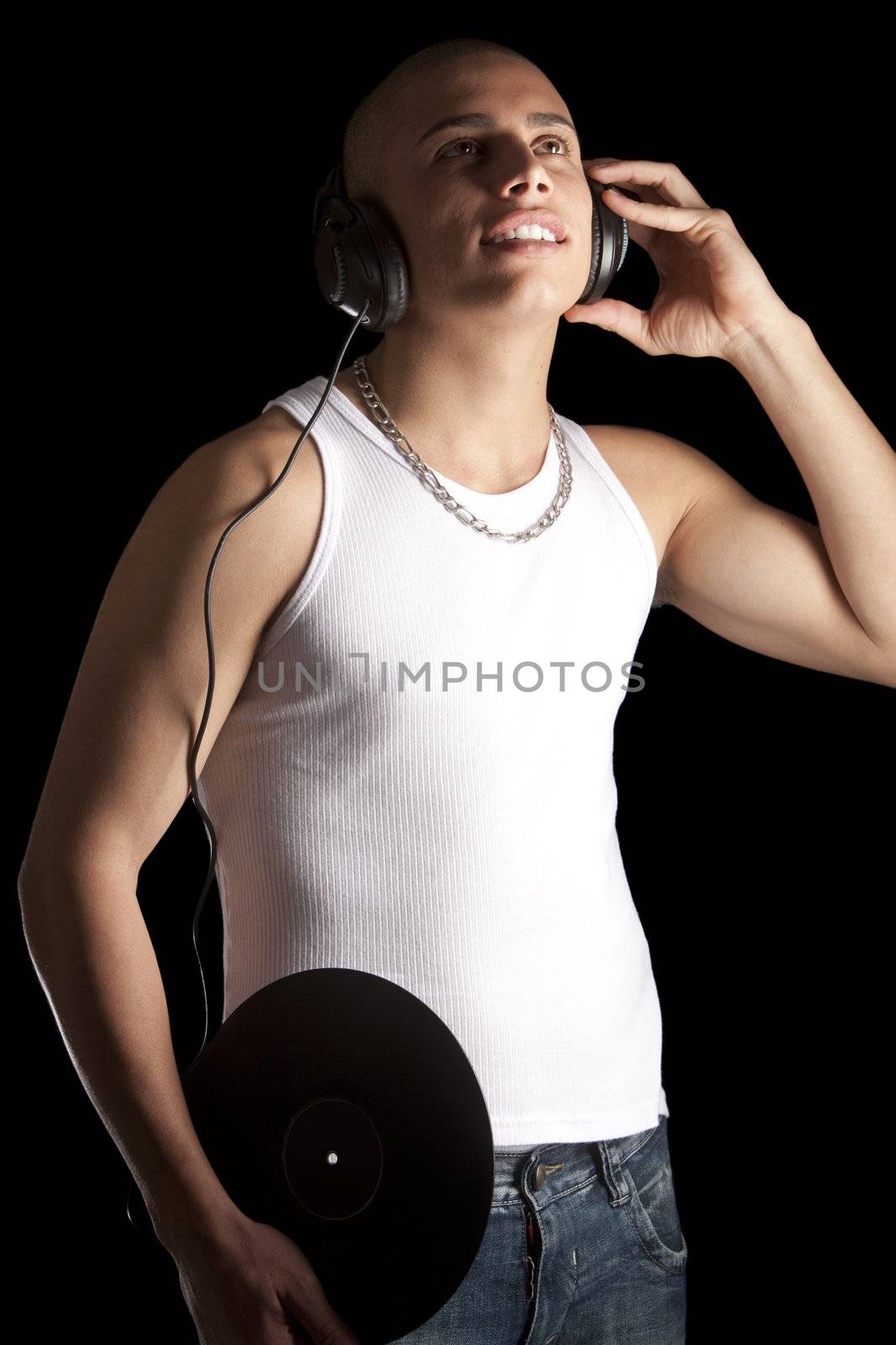 A good looking, muscular built, man on a black background with earphones.